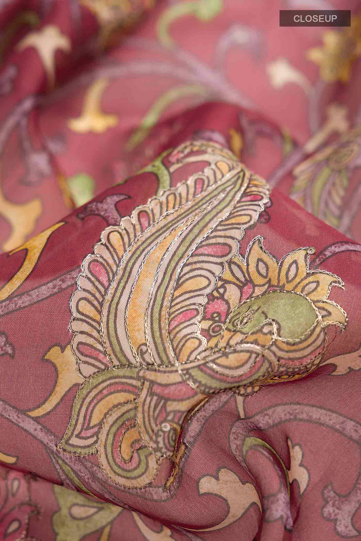 Close up of Maroon Organza Silk Saree with Floral Print on the body and Printed Border displaying folds