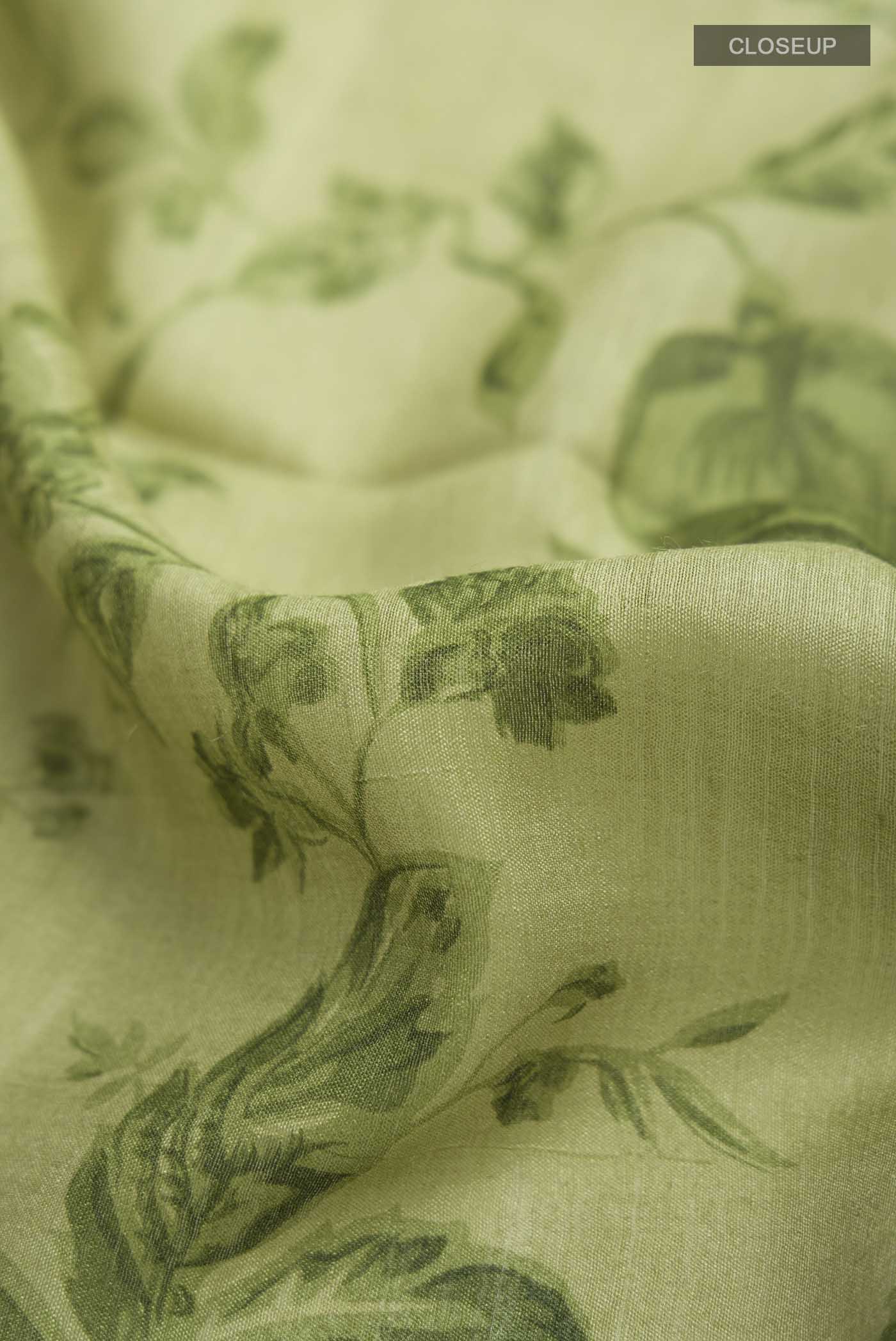 Close up of Green Tussar Silk Saree with Printed design on the body and Zari Border displaying folds