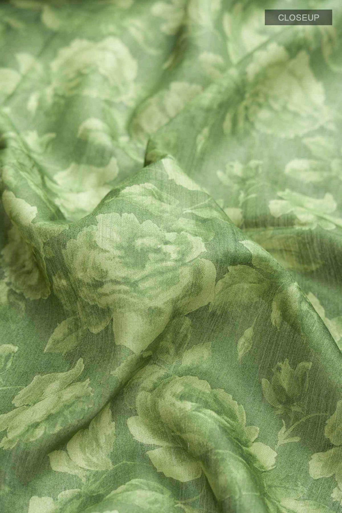 Close up of Green Bhagalpuri Tussar Silk Saree with Floral Print on the body and Zari Border displaying folds
