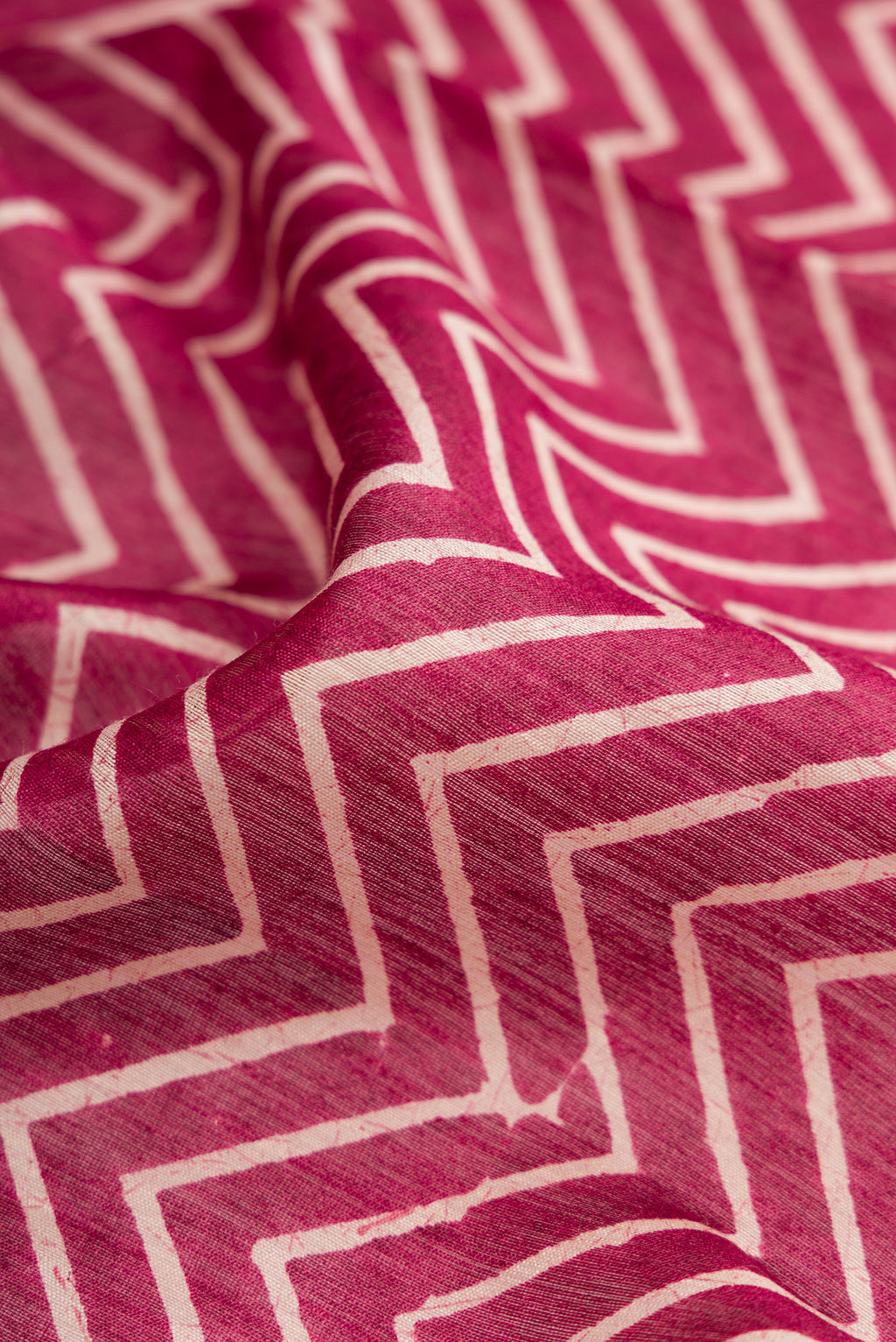 Close up of Burgundy Dual Tone Tussar Silk Saree with Printed design on the body and Zari Border.  displaying folds
