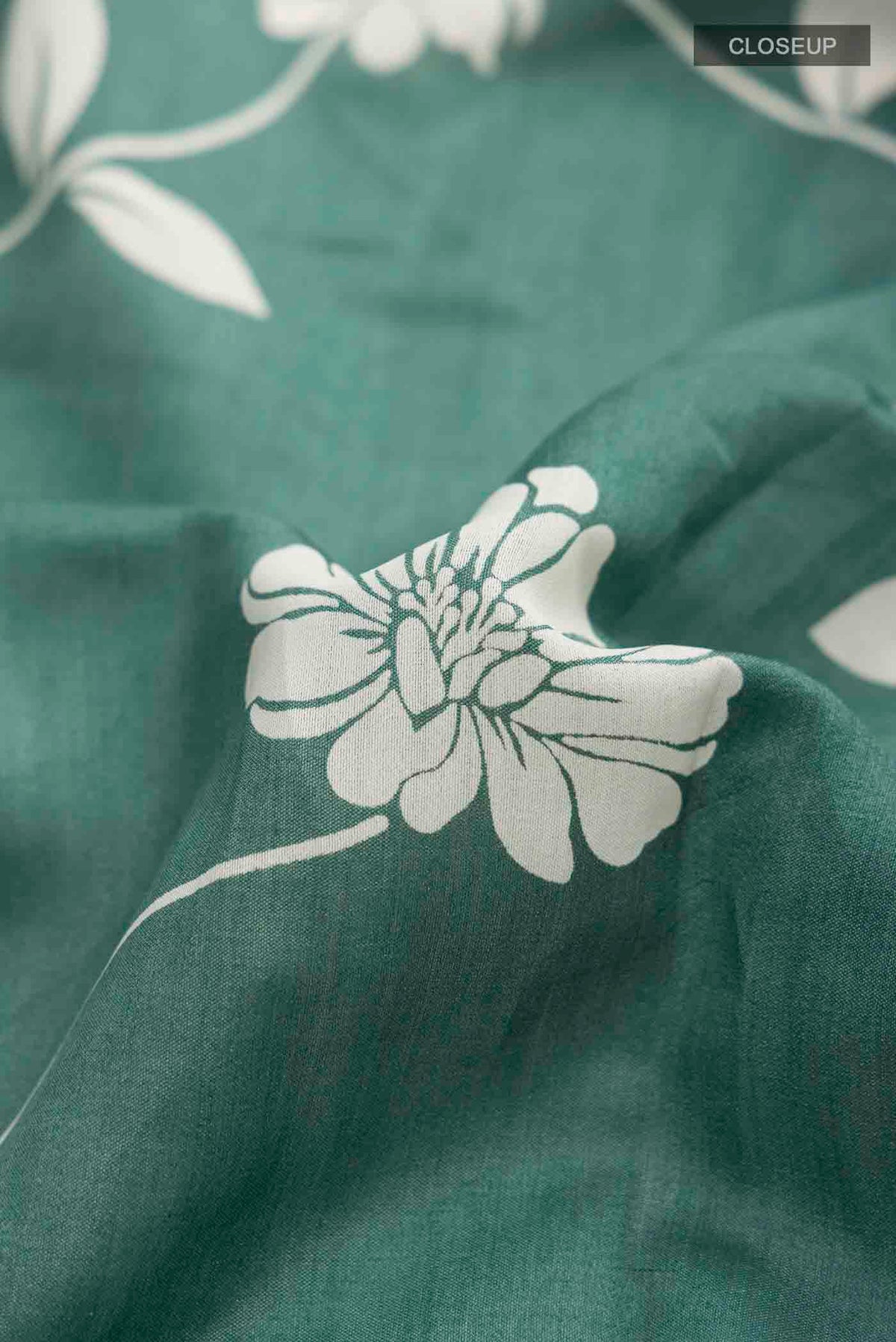 Close up of Green Tussar Silk Saree with Printed design on the body and Zari Border displaying folds