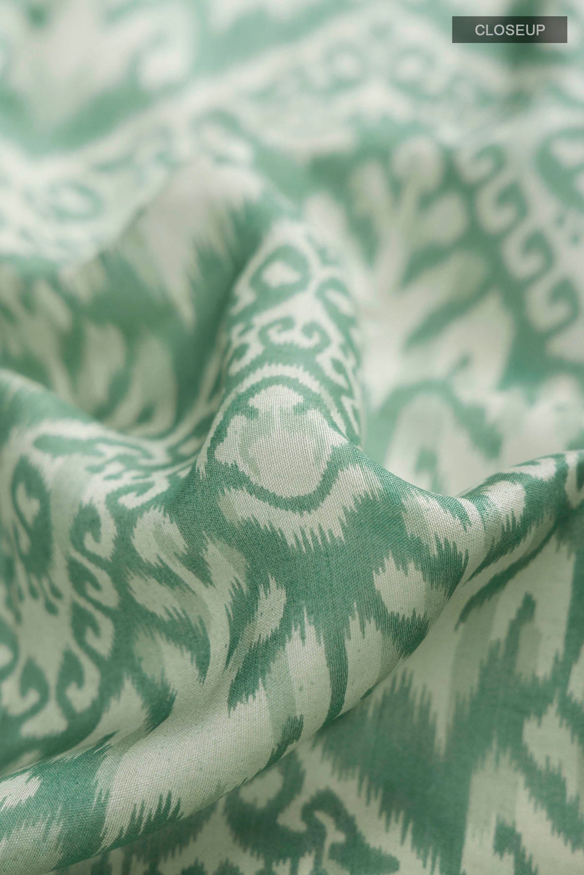 Close up of Green Tussar Silk Saree with Printed design on the body and Zari Border displaying folds