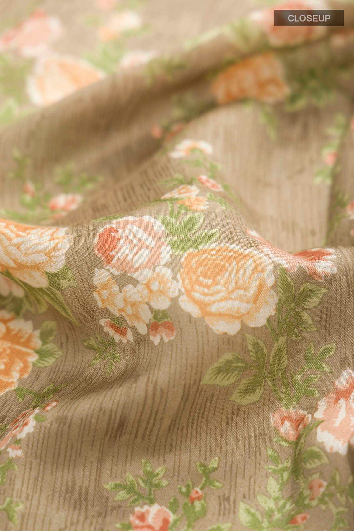 Close up of Brown Printed Silk Saree with Printed design on the body and Zari Border displaying folds