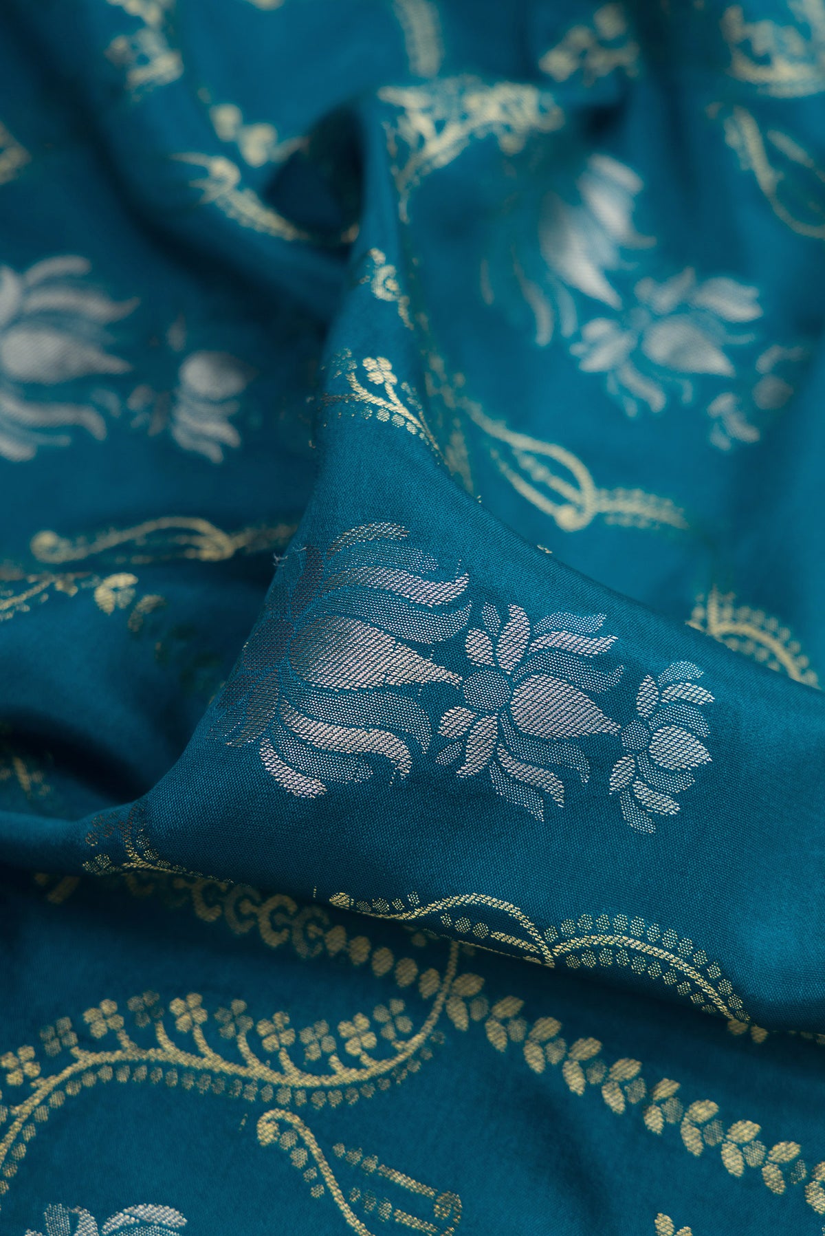 Close up of Peacock Blue Dual Tone Mysore Crepe Saree with Zari Brocade on the body and Zari Border.  displaying folds