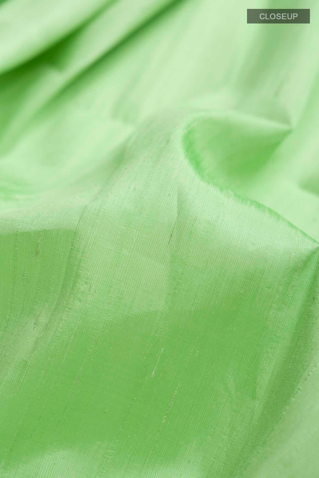 Close up of Green Raw Silk Saree with Plain Body and Zari Border displaying folds