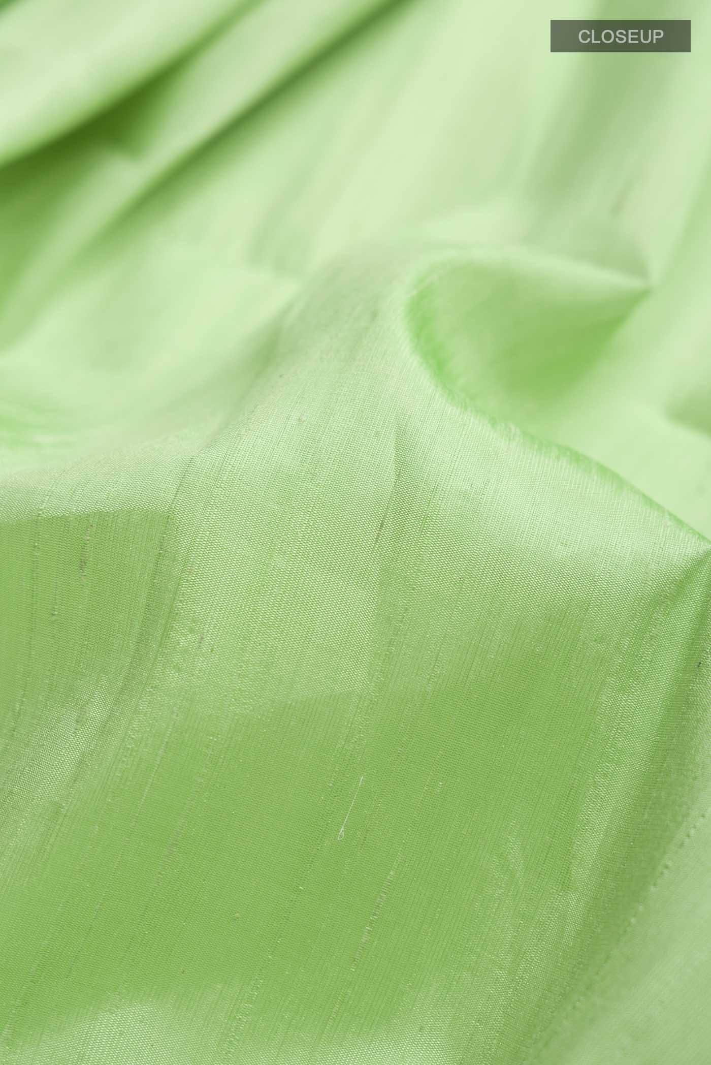 Close up of Green Raw Silk Saree with Plain Body and Zari Border displaying folds
