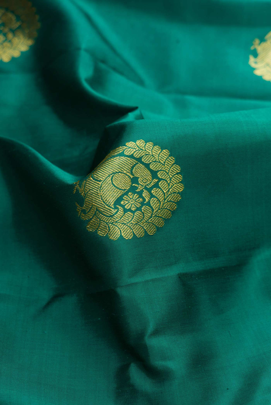 Close up of Green Dual Tone Kanchipuram Silk Saree with Zari Butta on the body and Zari Border displaying folds