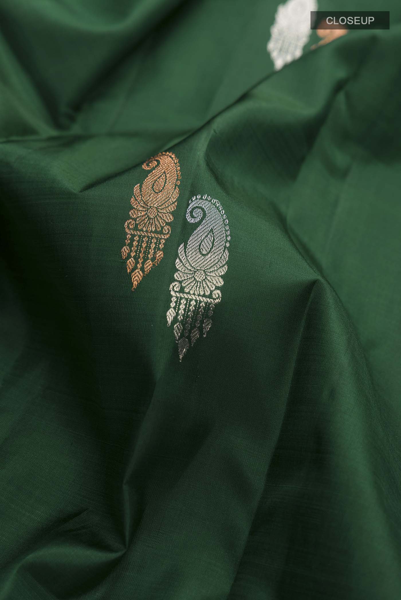 Close up of Green Kanchipuram Silk Saree with Zari Butta on the body and Zari Border displaying folds