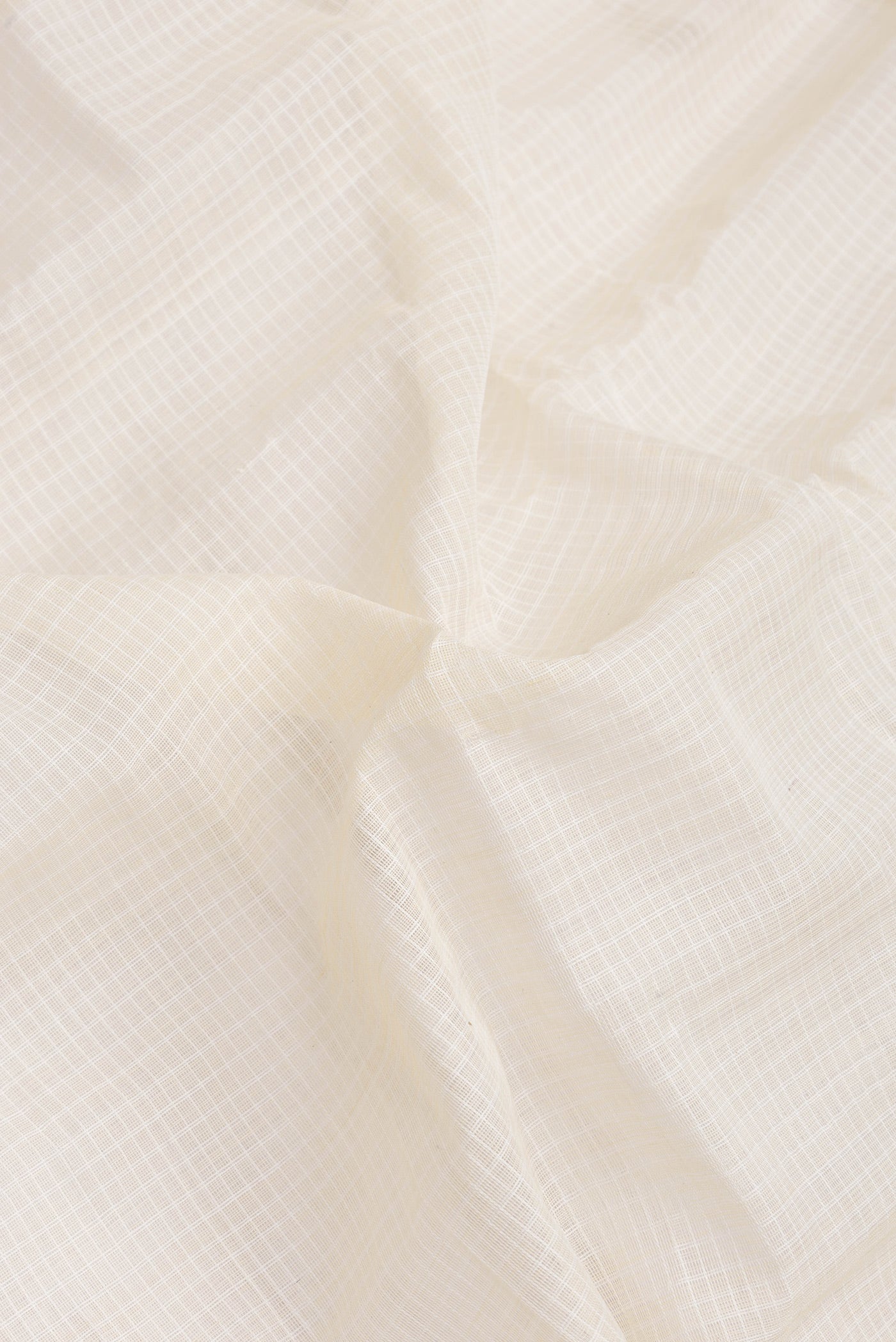 Close up of Off White Dual Tone Kanchipuram Silk Saree with Checked design on the body and Zari Border.  displaying folds