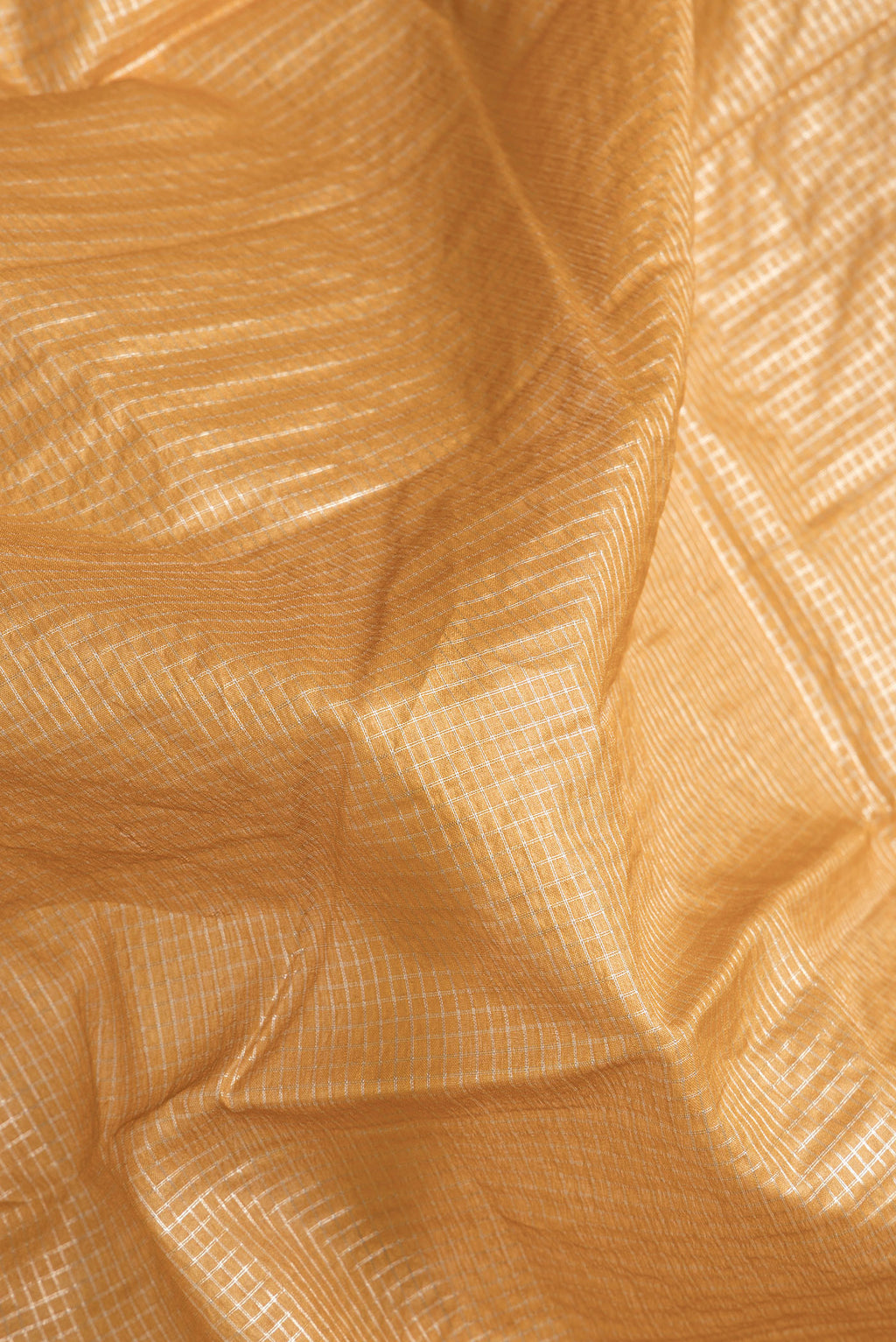 Close up of Gold Dual Tone Tussar Silk Saree with Checked design on the body and Zari Border.  displaying folds