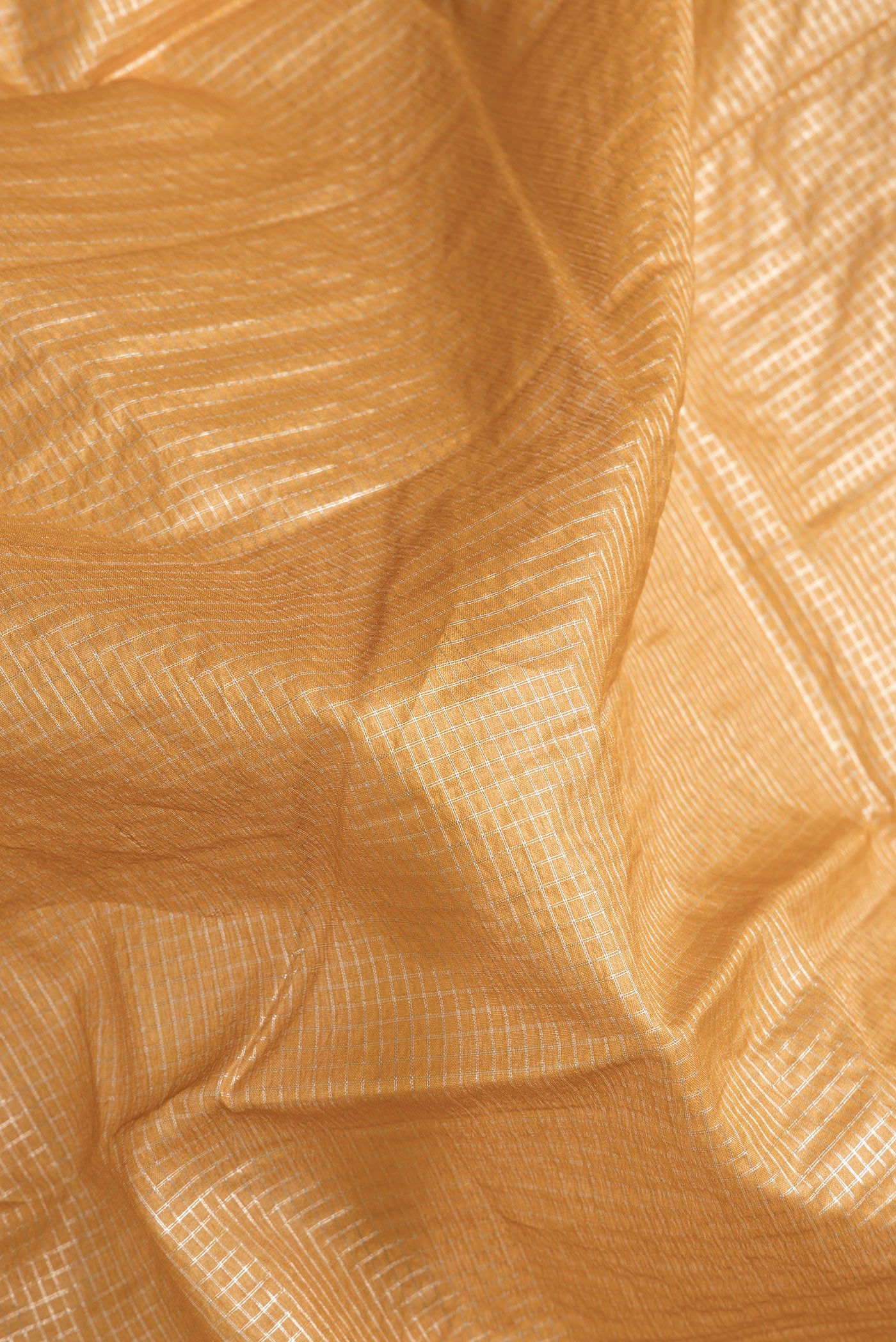 Close up of Gold Dual Tone Tussar Silk Saree with Checked design on the body and Zari Border.  displaying folds