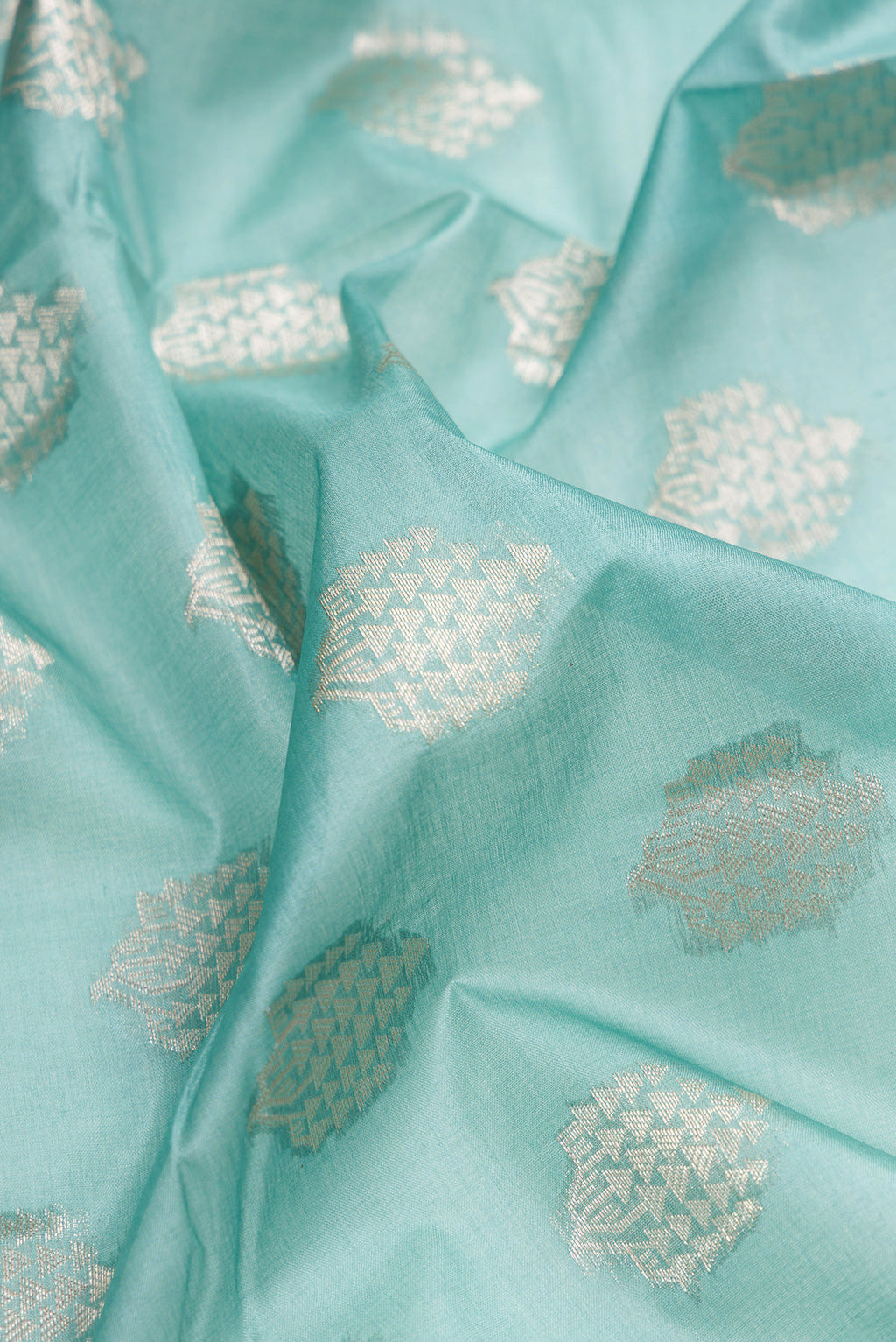 Close up of Sky Blue Tussar Silk Saree with Zari Butta on the body and Zari Border.  displaying folds