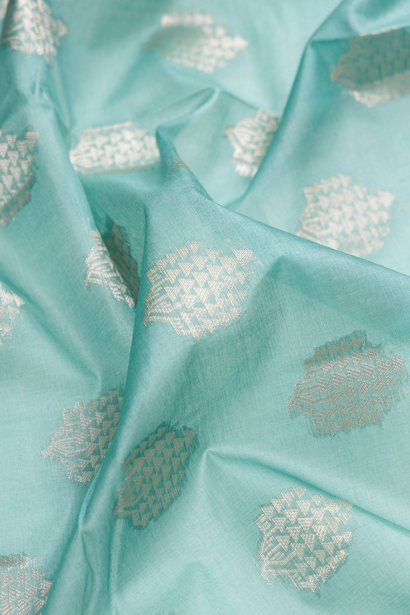 Close up of Sky Blue Tussar Silk Saree with Zari Butta on the body and Zari Border.  displaying folds