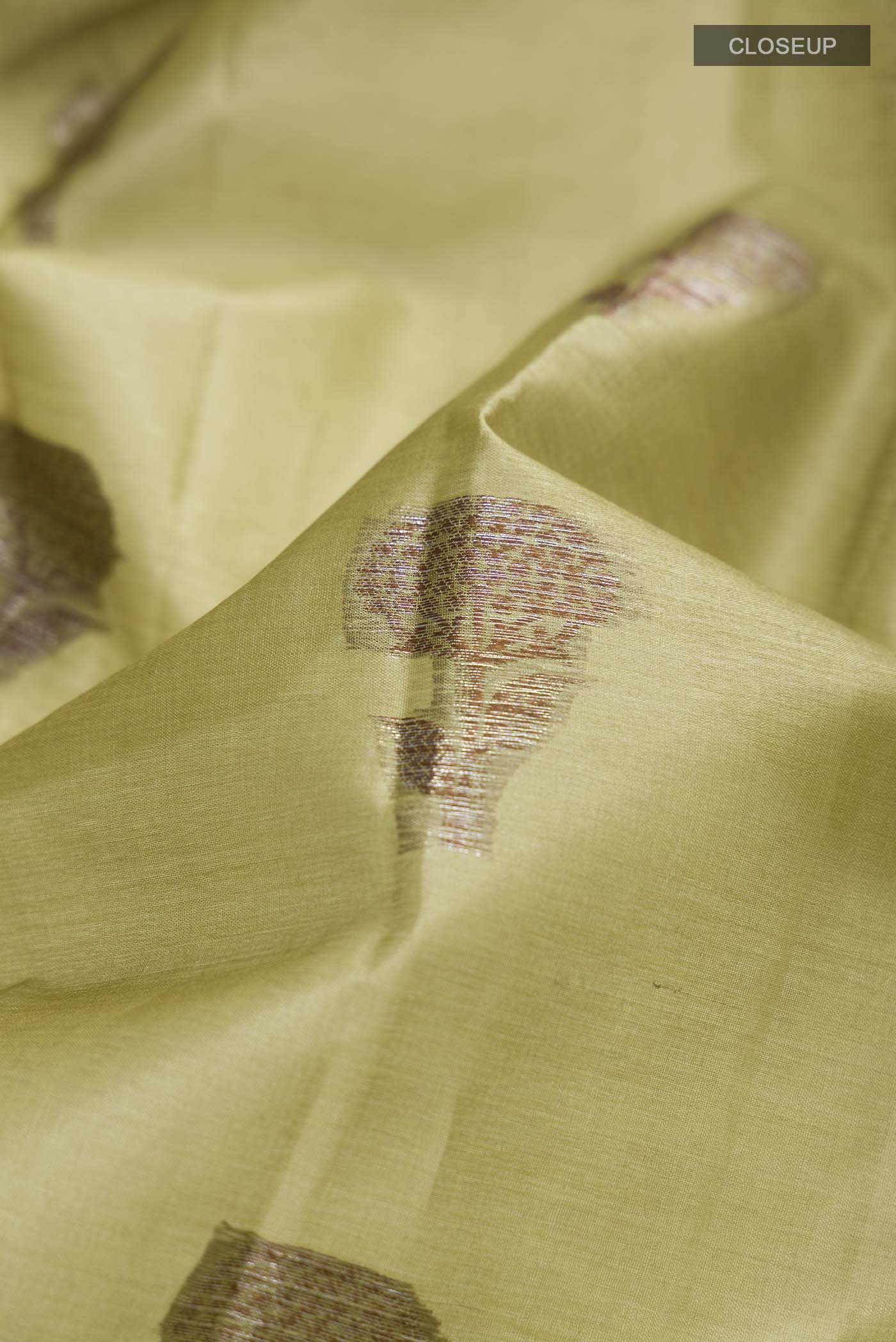 Close up of Green Tussar Silk Saree with Zari Butta on the body and Zari Border displaying folds