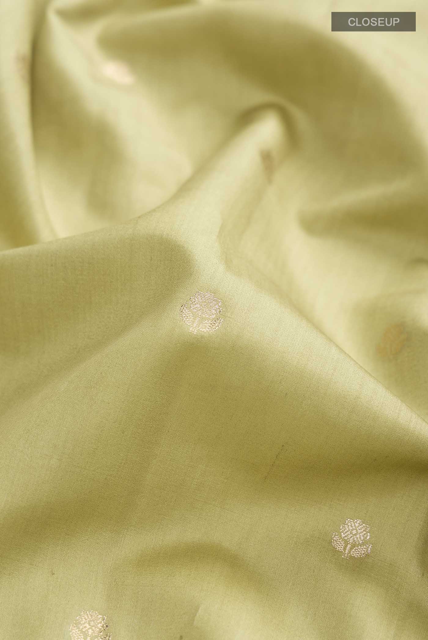 Close up of Green Banarasi Raw Silk Saree with Zari Butta on the body and Zari Border displaying folds
