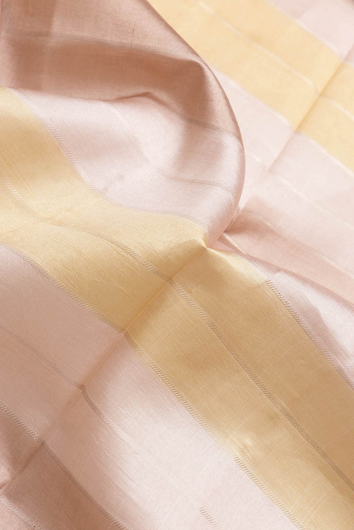 Close up of Rose Gold Dual Tone Tussar Silk Saree with Stripes on the body and Zari Border.  displaying folds