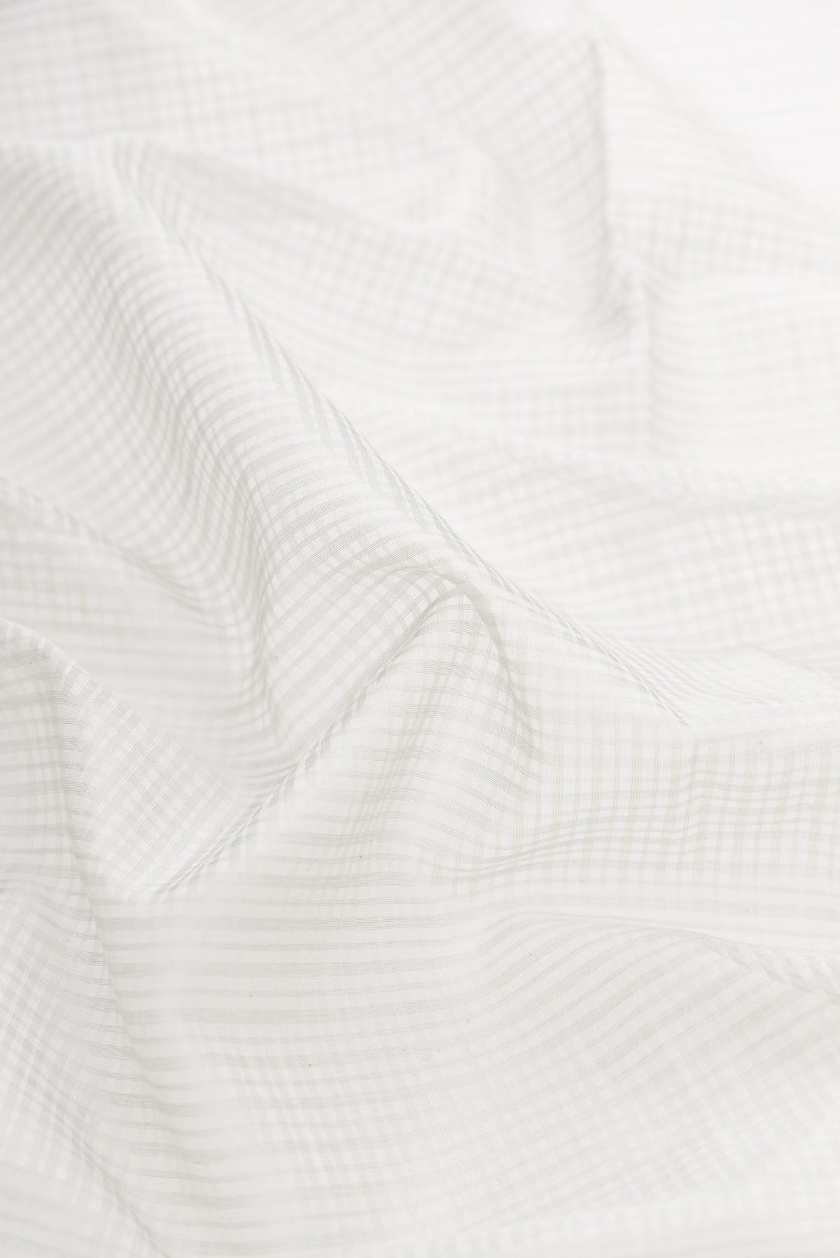 Close up of Grey Dual Tone Maheshwari Silk Saree with Checked design on the body and Zari Border displaying folds