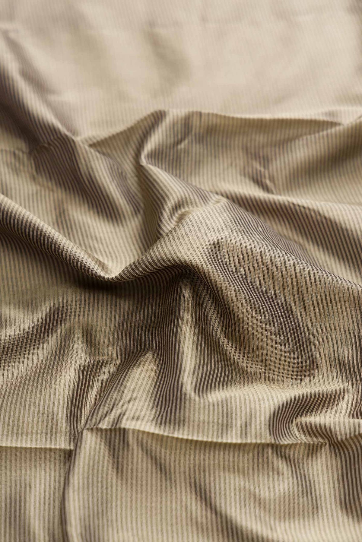 Close up of Dark Beige Dual Tone Maheshwari Silk Saree with Stripes on the body and Zari Border displaying folds