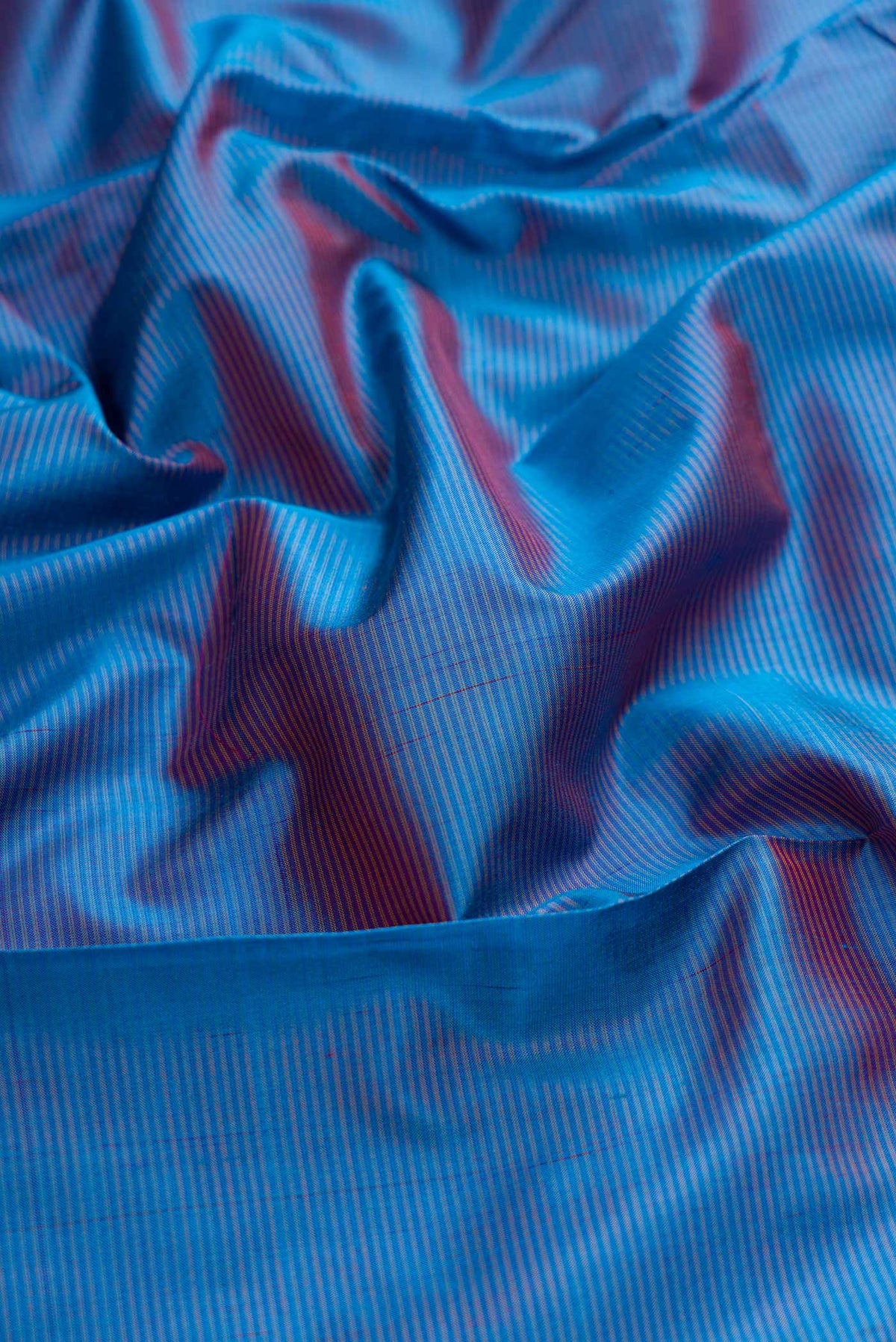 Close up of Blue Dual Tone Maheshwari Silk Saree with Stripes on the body and Zari Border displaying folds