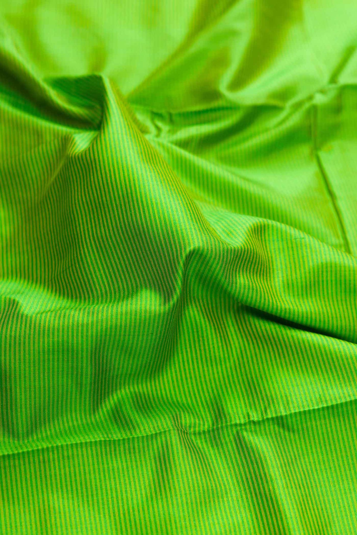 Close up of Parrot Green Dual Tone Maheshwari Silk Saree with Stripes on the body and Zari Border displaying folds