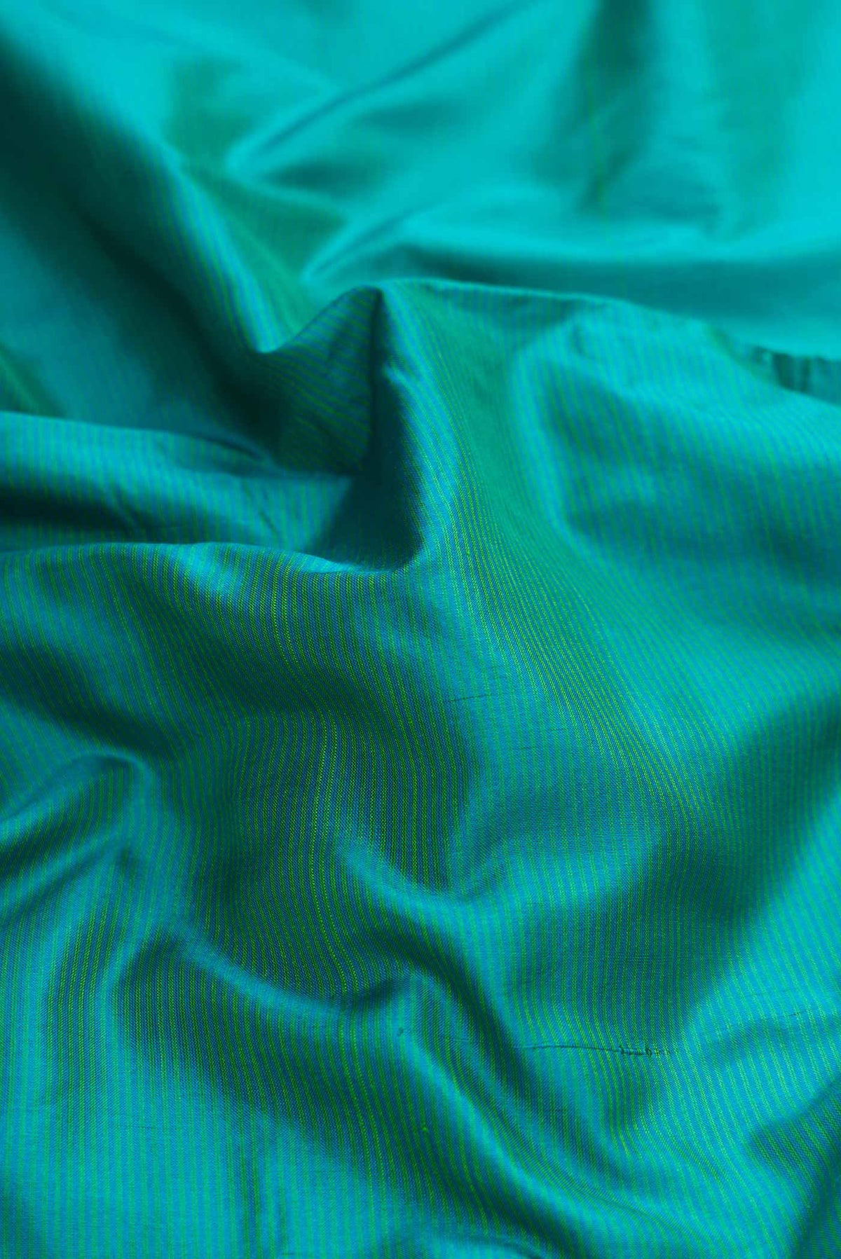 Close up of Green Dual Tone Maheshwari Silk Saree with Stripes on the body and Zari Border displaying folds