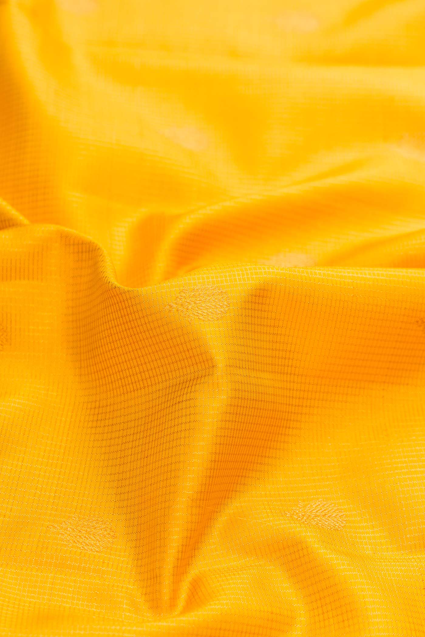 Close up of Yellow Dual Tone Kanchipuram Silk Saree with Zari Butta on the body and Zari Border displaying folds