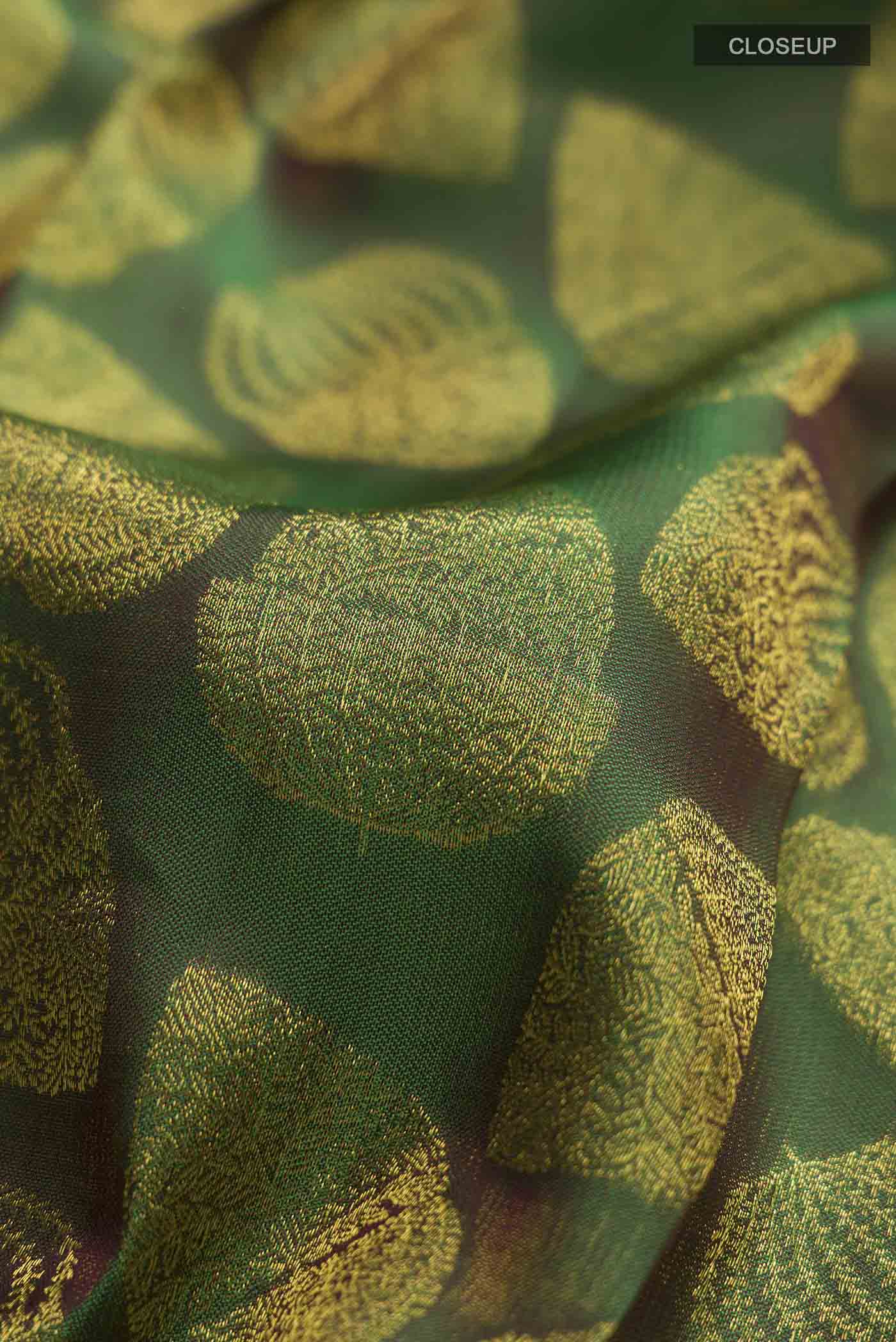 Close up of Green Kanchipuram Silk Saree with Zari Butta on the body and Zari Border displaying folds