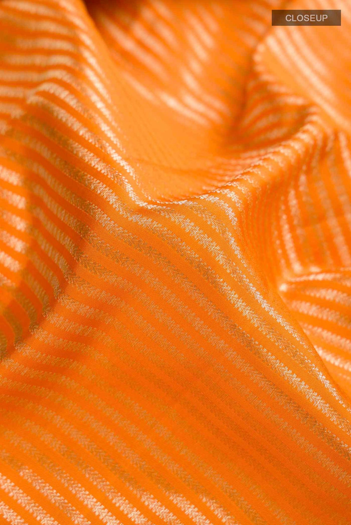 Close up of Orange Kanchipuram Silk Saree with Stripes on the body and Zari Border displaying folds