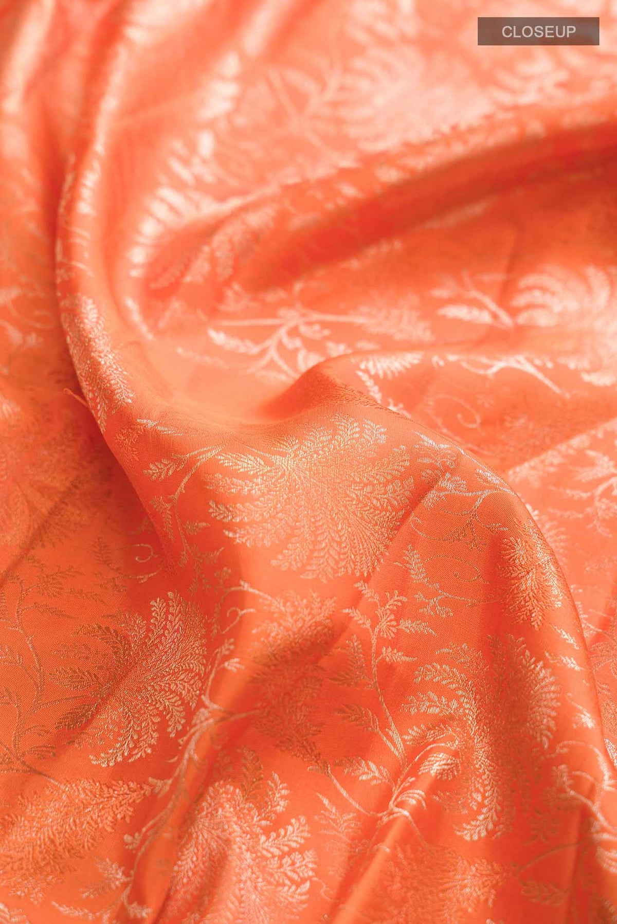 Close up of Orange Kanchipuram Silk Saree with Zari Brocade on the body and Zari Border displaying folds