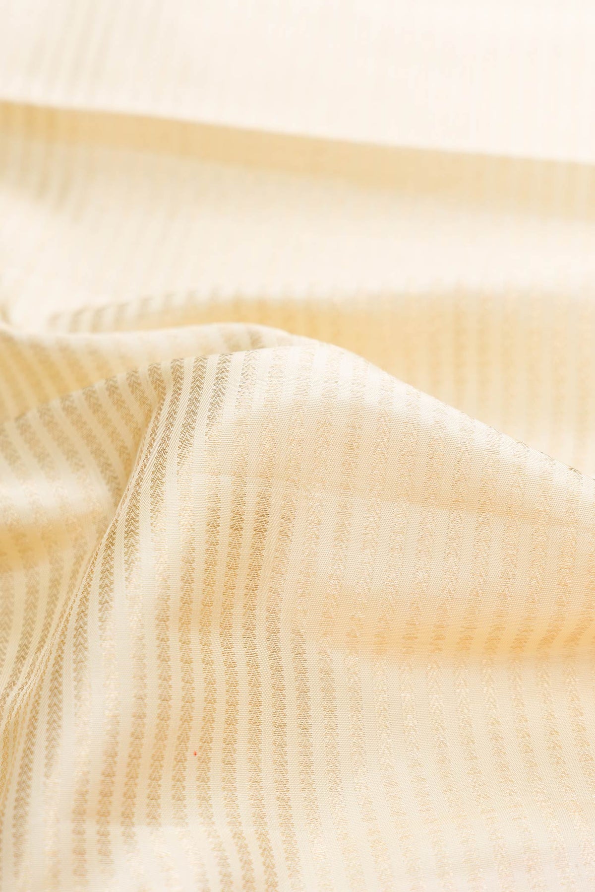 Close up of Off White Dual Tone Kanchipuram Silk Saree with Zari Brocade on the body and Zari Border displaying folds