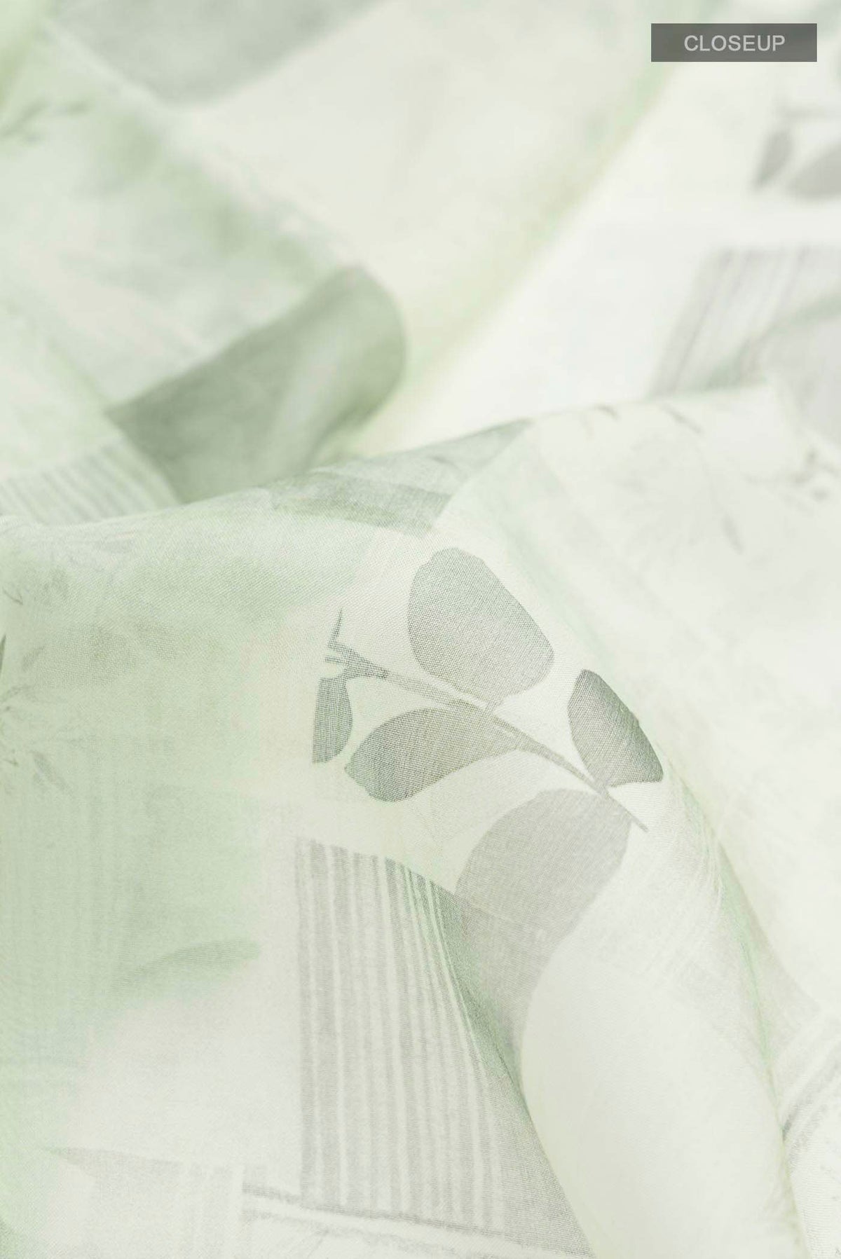 Close up of Green Organza Silk Saree with Printed design on the body and Plain Border displaying folds