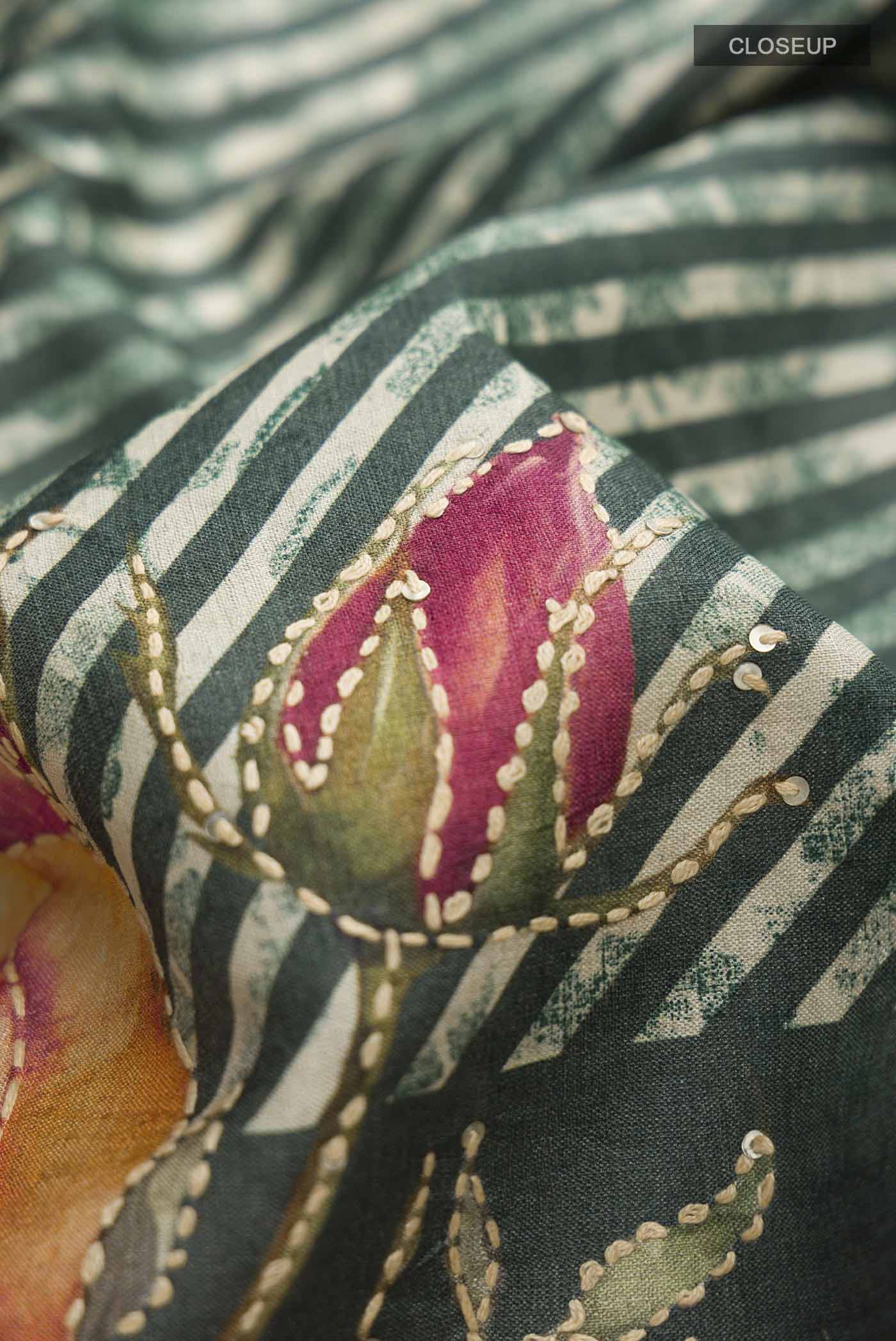 Close up of Green Tussar Silk Saree with Embroidery on the body and Zari And Thread Border displaying folds