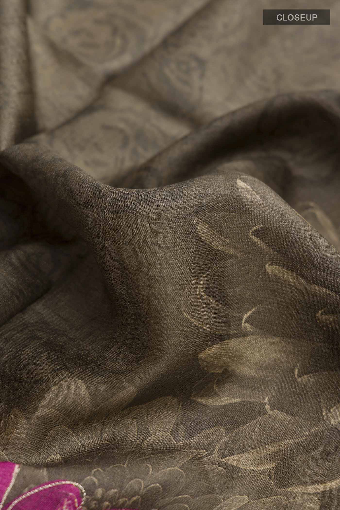 Close up of Green Tussar Silk Saree with Printed design on the body and Embroidery Border displaying folds