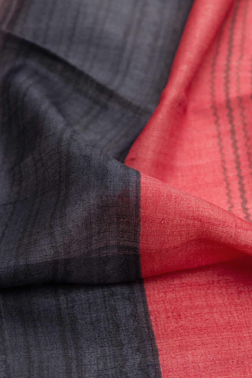 Close up of Maroon,Brown and Black Color Tussar Silk Saree with Printed design on the body and Embroidery Border.  displaying folds
