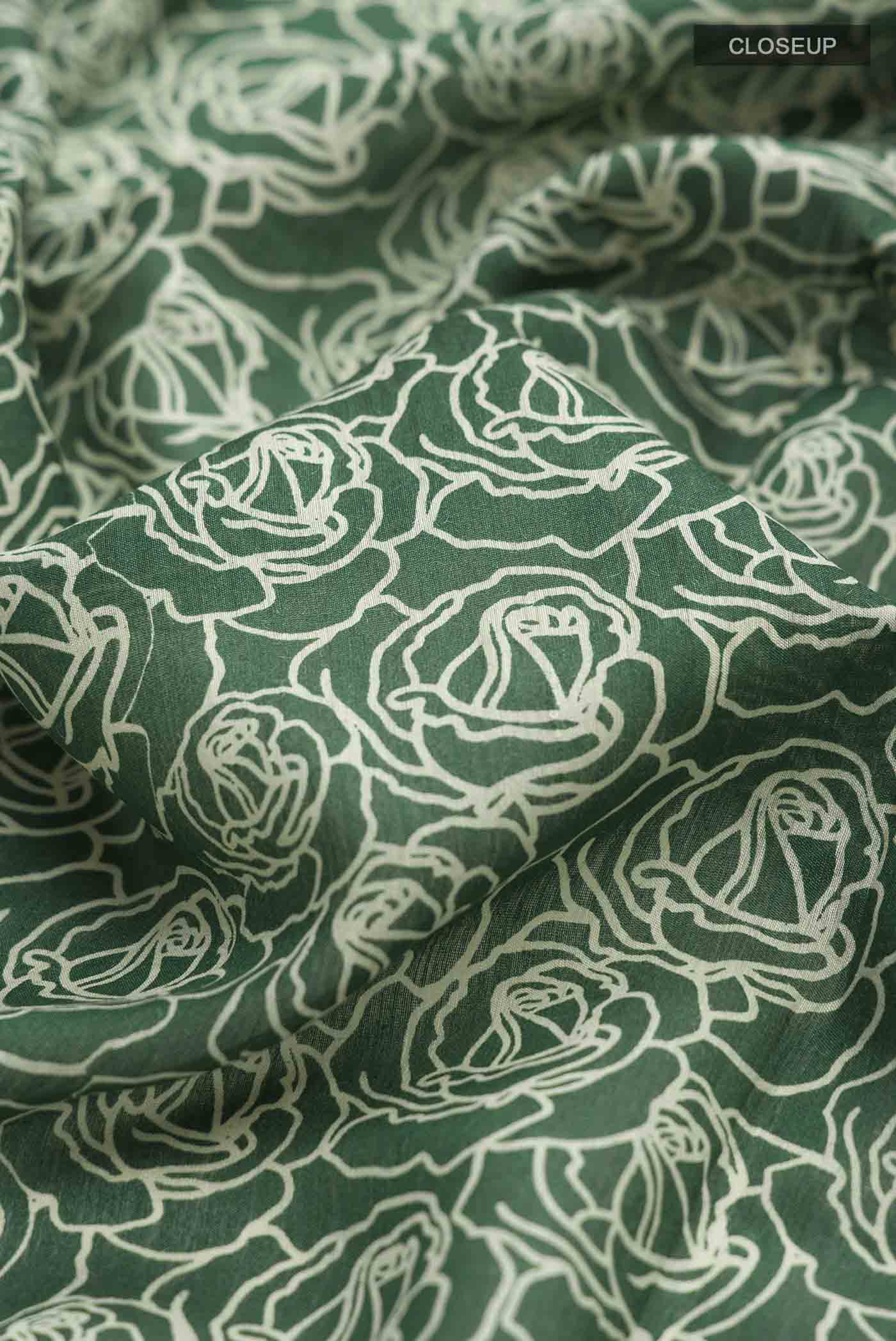Close up of Green Tussar Silk Saree with Printed design on the body and Zari Border displaying folds