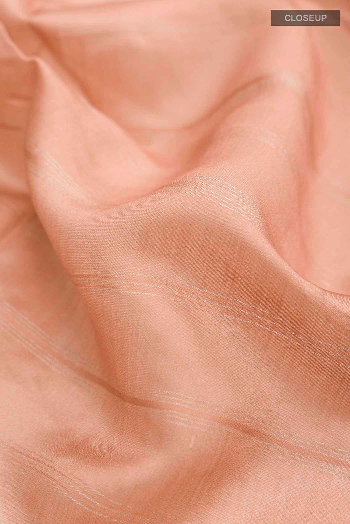 Close up of Peach Tussar Silk Saree with Zari Butta on the body and Zari Border displaying folds