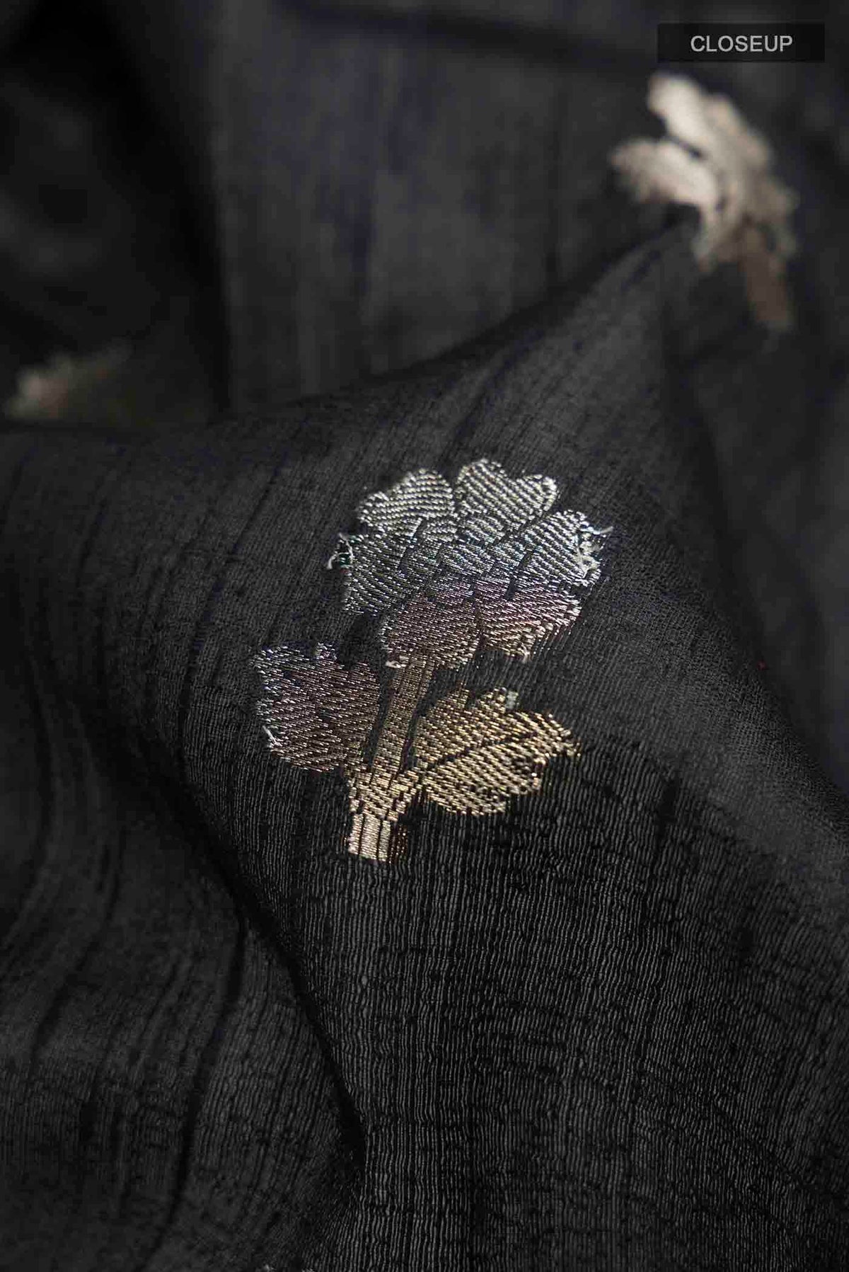 Close up of Black Tussar Silk Saree with Zari Butta on the body and Zari Border displaying folds