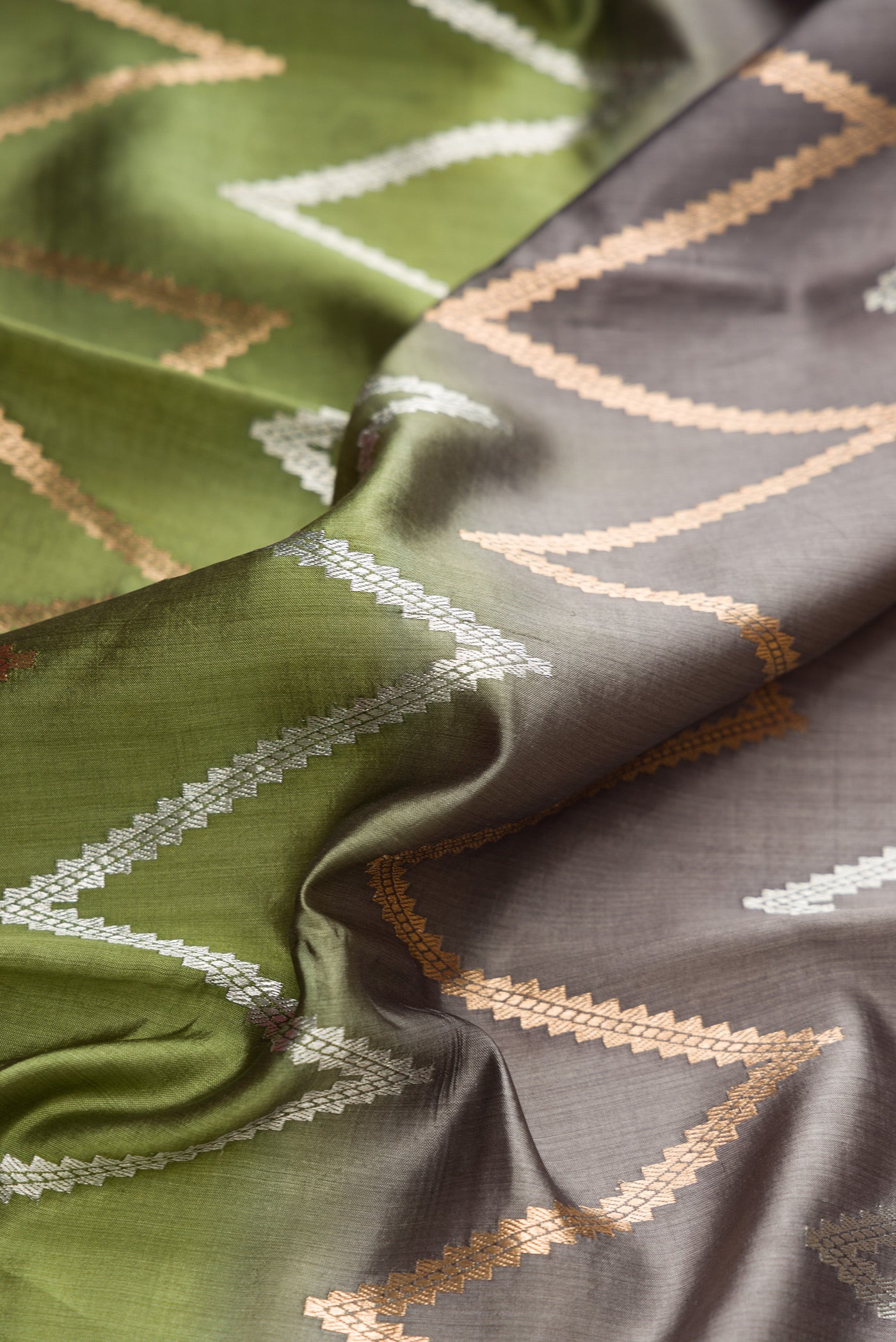 Close up of Sandal, Grey and Green Color Tussar Silk Saree with Zari Butta on the body and Plain Border.  displaying folds
