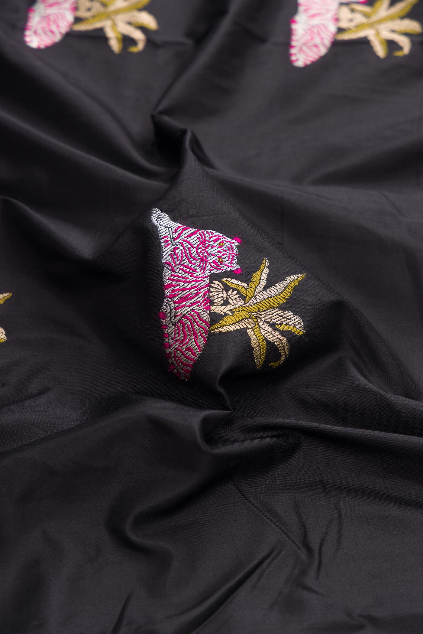 Close up of Black Dual Tone Banarasi Silk Saree with Zari And Thread Butta on the body and Zari Border displaying folds
