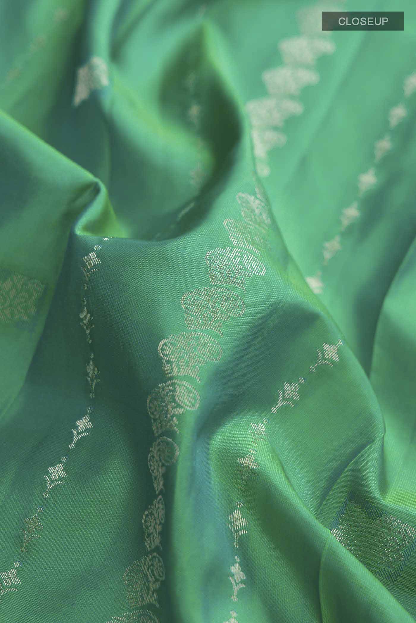 Close up of Green Kanchipuram Silk Saree with Zari Butta on the body and Zari Border displaying folds