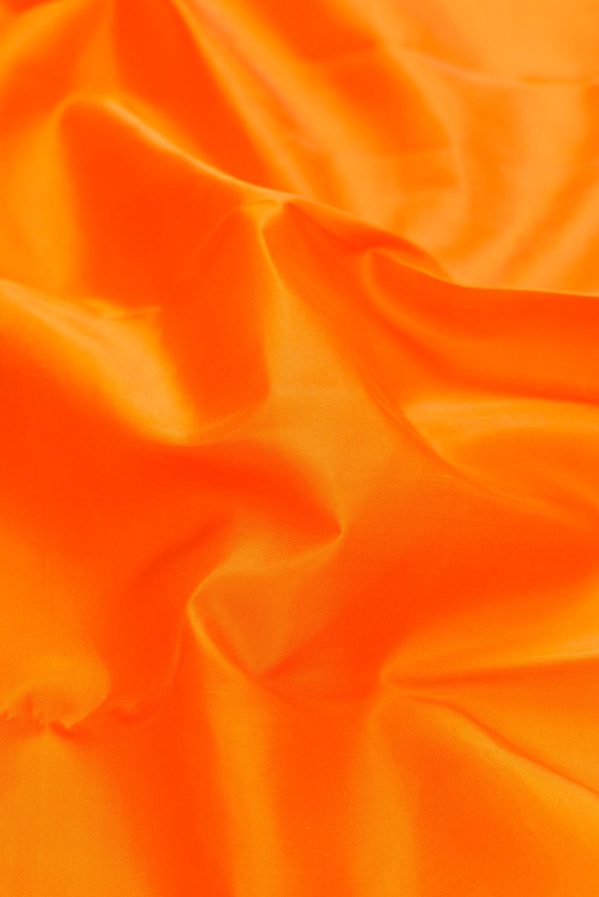 Close up of Orange Dual Tone Kanchipuram Silk Saree with Plain Body and Ganga Jamuna Border.  displaying folds