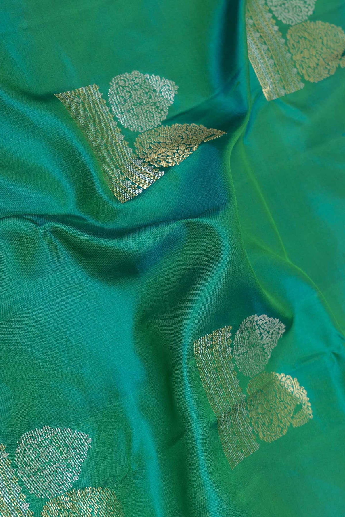 Close up of Green Dual Tone Kanchipuram Saree with Zari Butta on the body and Zari Border displaying folds