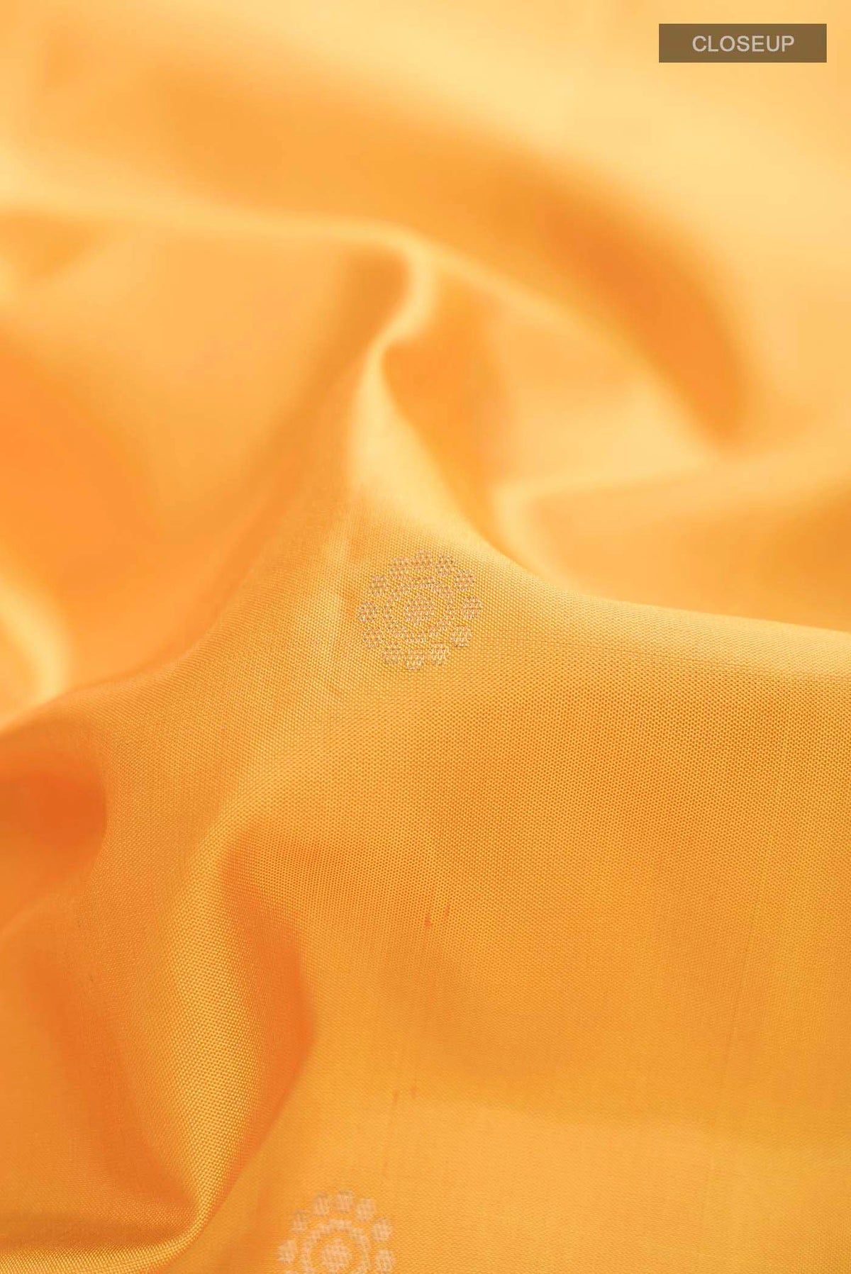 Close up of Yellow Soft Silk Saree with Zari Butta on the body and Zari Border displaying folds