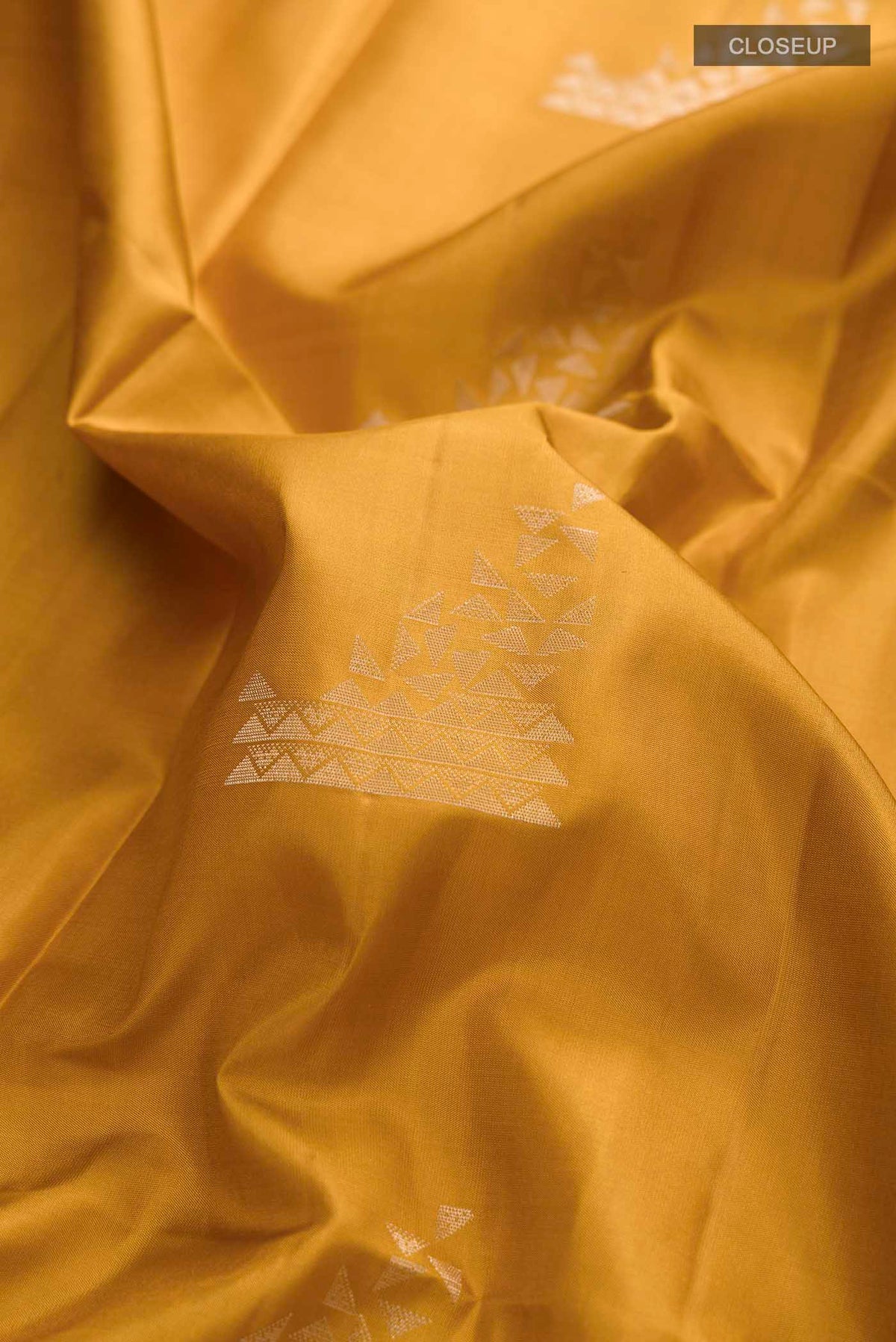 Close up of Mustard Soft Silk Saree with Zari Butta on the body and Zari Border displaying folds