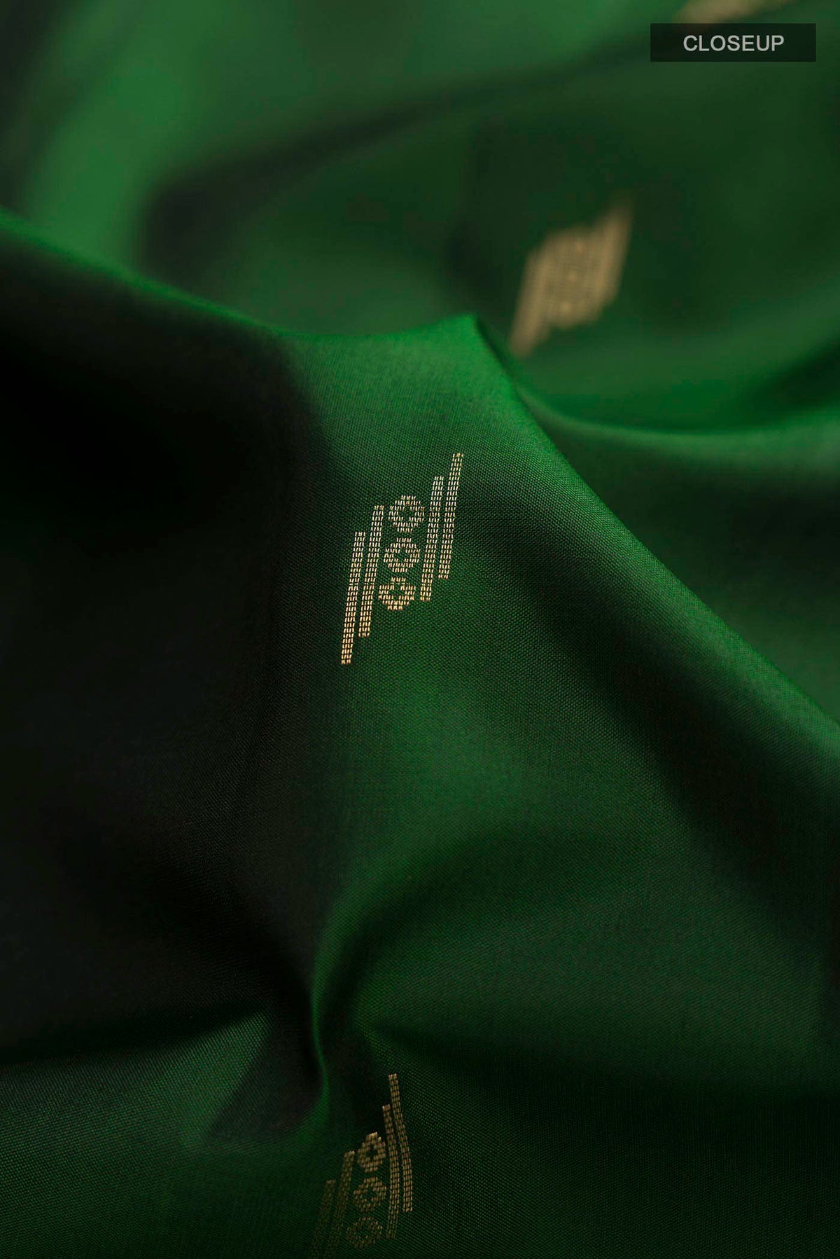 Close up of Green Soft Silk Saree with Zari Butta on the body and Zari Border displaying folds