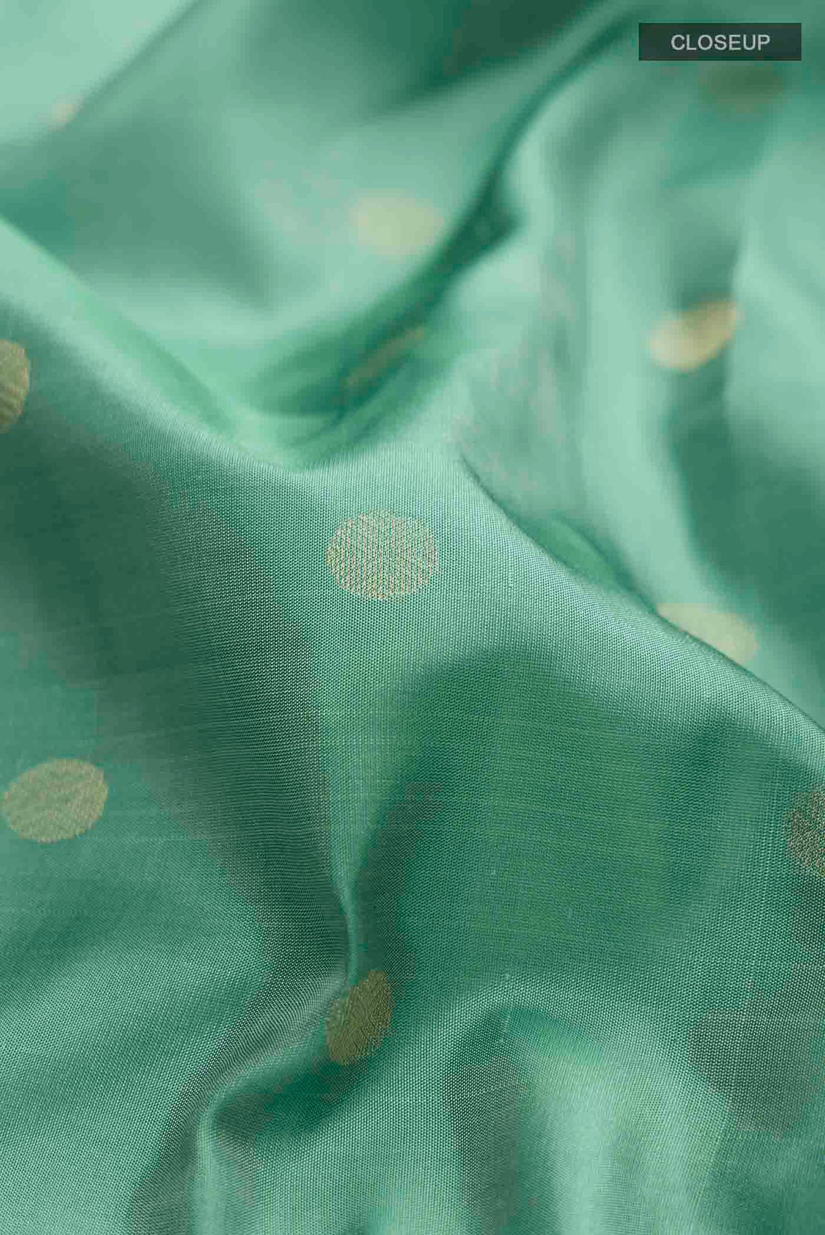 Close up of Green Soft Silk Saree with Zari Butta on the body and Zari Border displaying folds
