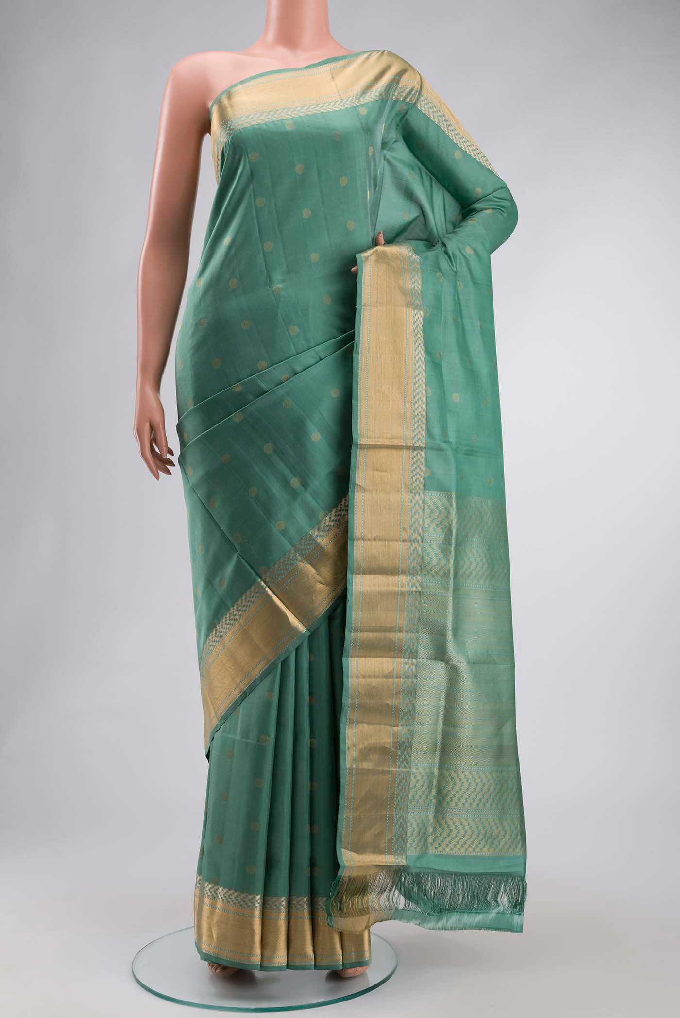 Green Soft Silk Saree with Zari Butta on the body and Zari Border displayed on a mannequin