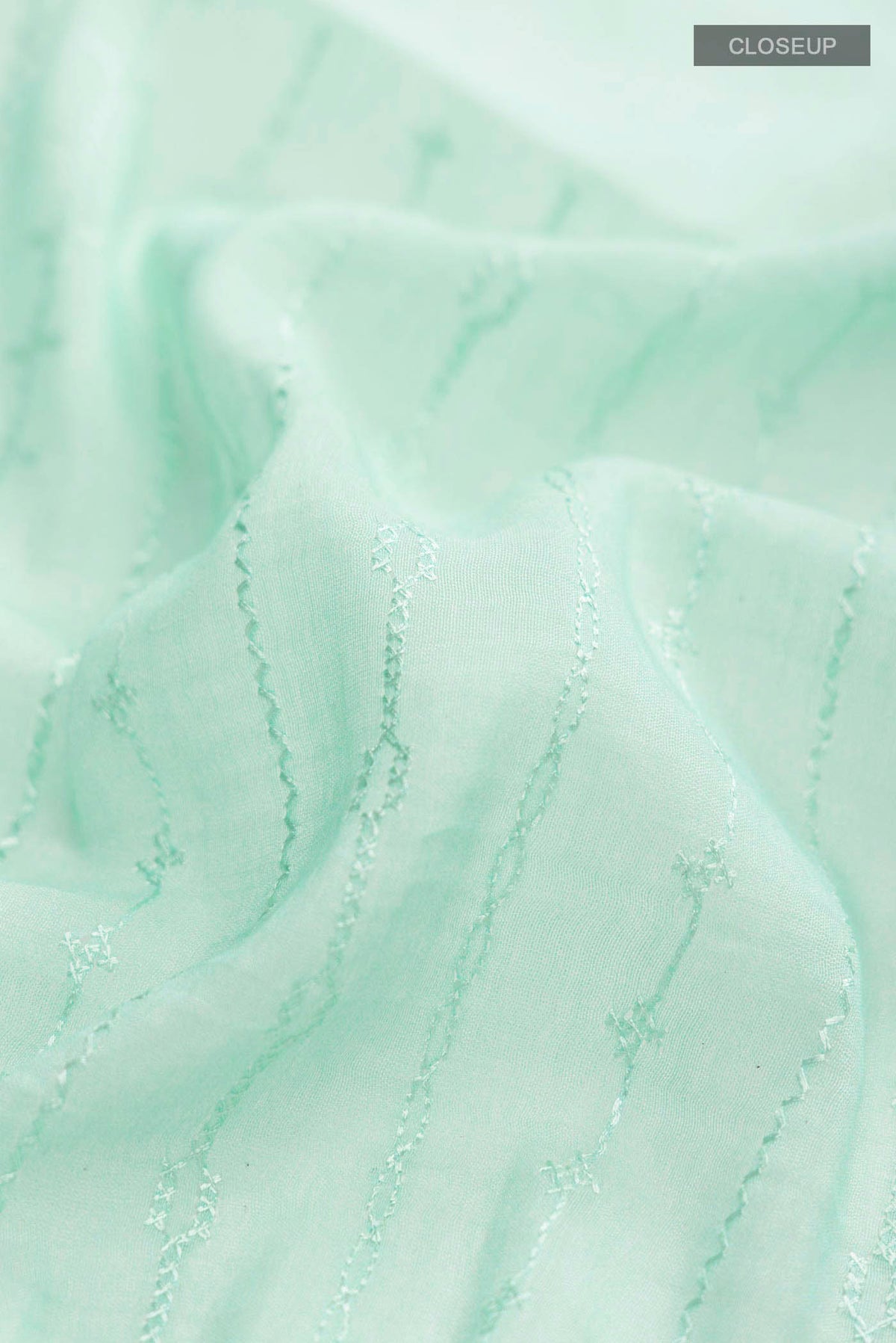 Close up of Green Silk Cotton Saree with Printed design on the body and Zari Border displaying folds