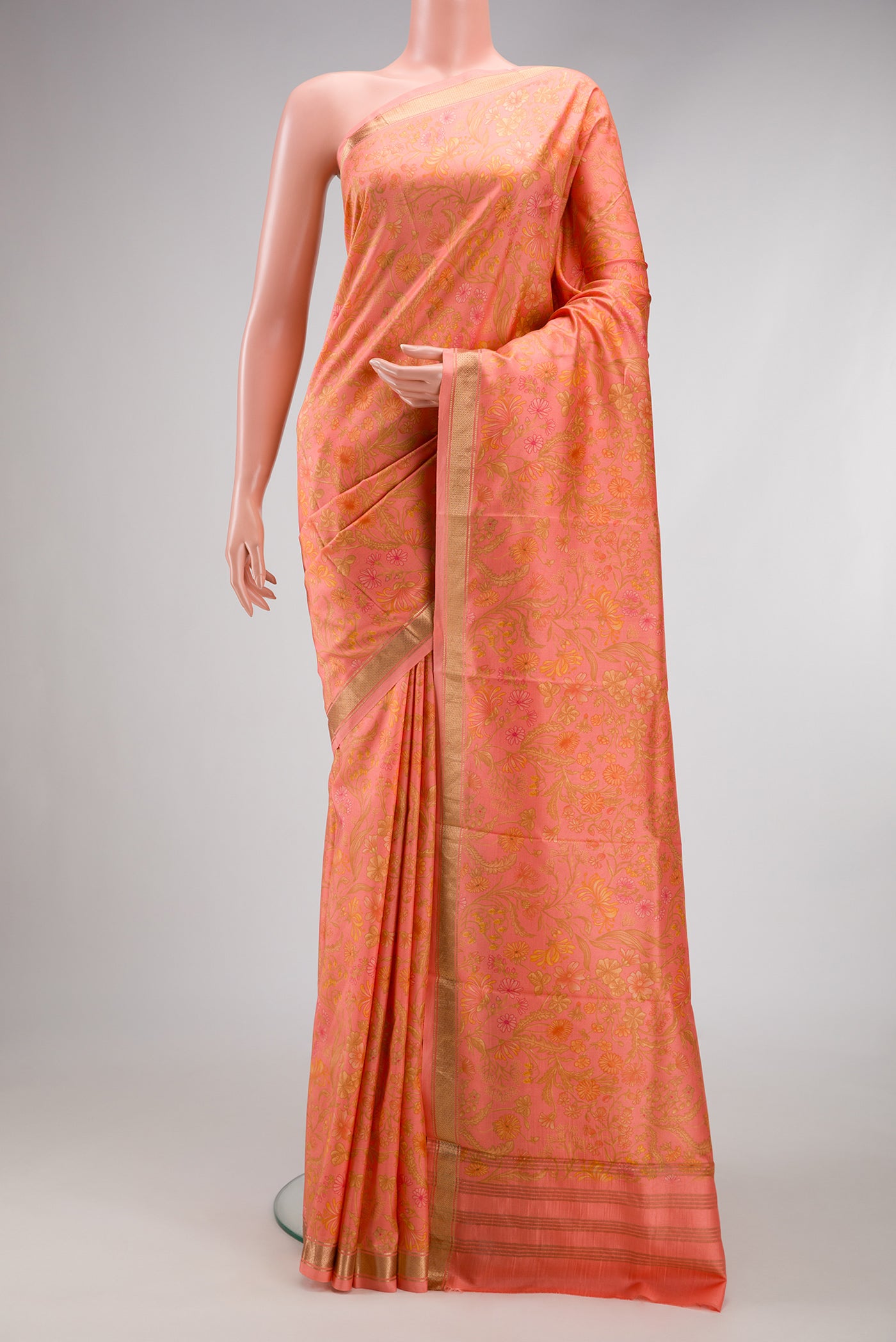 Peach Printed Silk Saree with Printed design on the body and Zari Border.  displayed on a mannequin