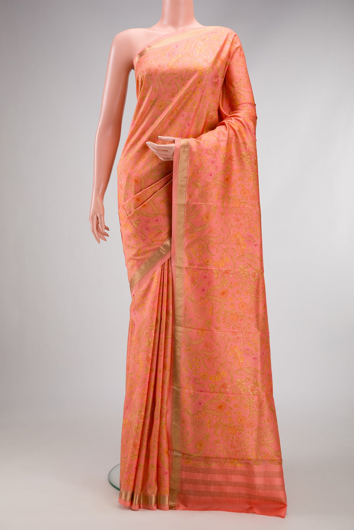 Peach Printed Silk Saree with Printed design on the body and Zari Border.  displayed on a mannequin